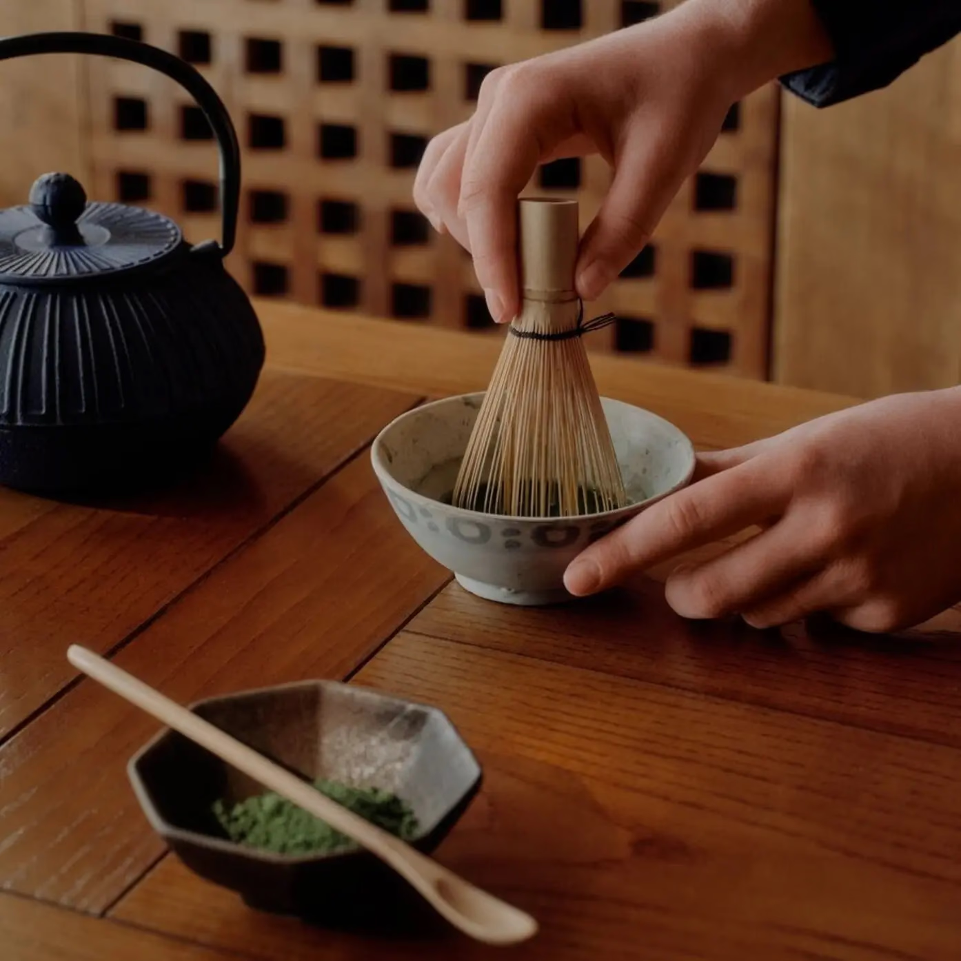 Aman Le Mélézin: Japanese tea ceremony with a bamboo whisk stirring matcha beside a cast iron teapot