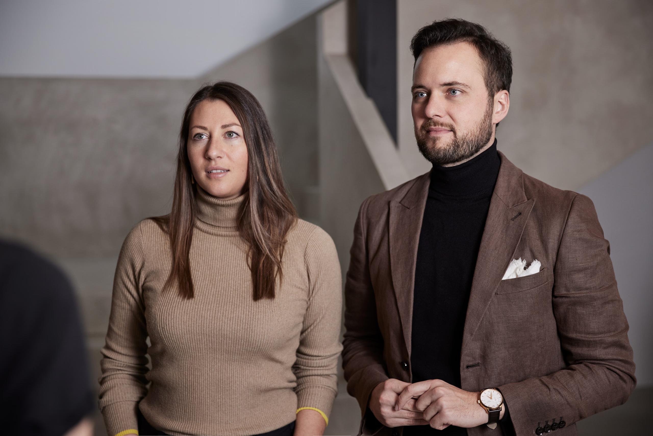 Forestis: two people standing in the hotel’s minimalist modern interior with neutral wall finishes visible behind