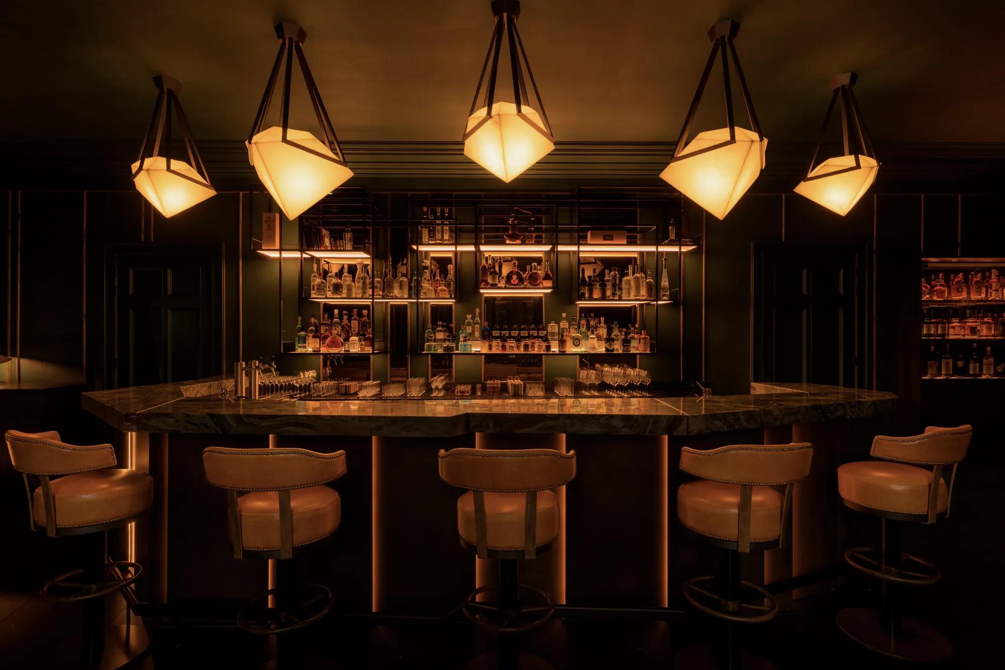 Rosewood Amsterdam: the Advocatuur bar with glass pendant lamps, a marble counter, and leather stools