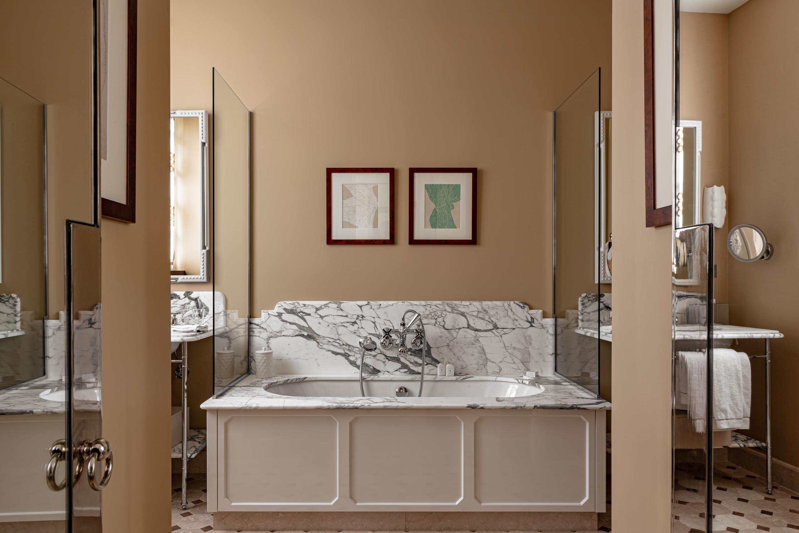 Saint James: bedroom with four-poster metal bed, marble headboard, and twin mirrors above nightstands