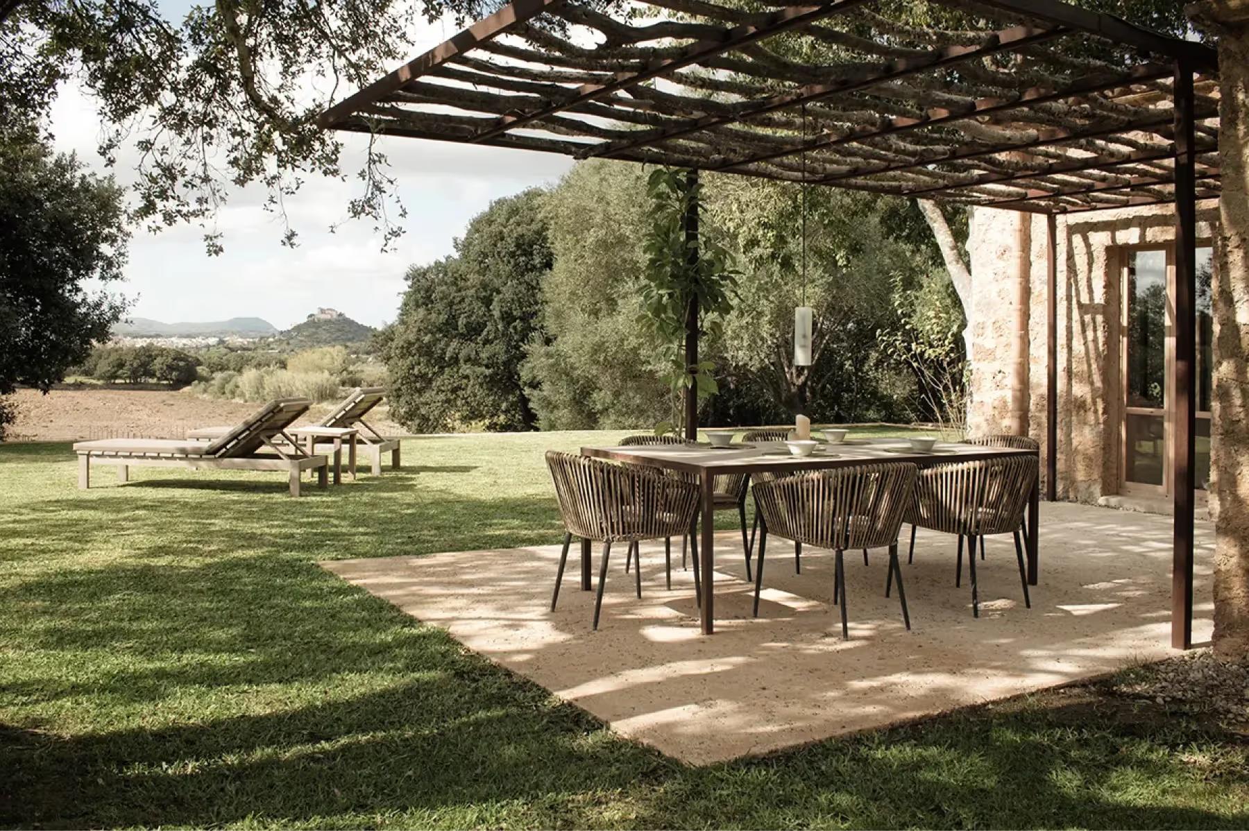 Outdoor dining pavilion with timber overhead structure, open sides, and estate grounds beyond