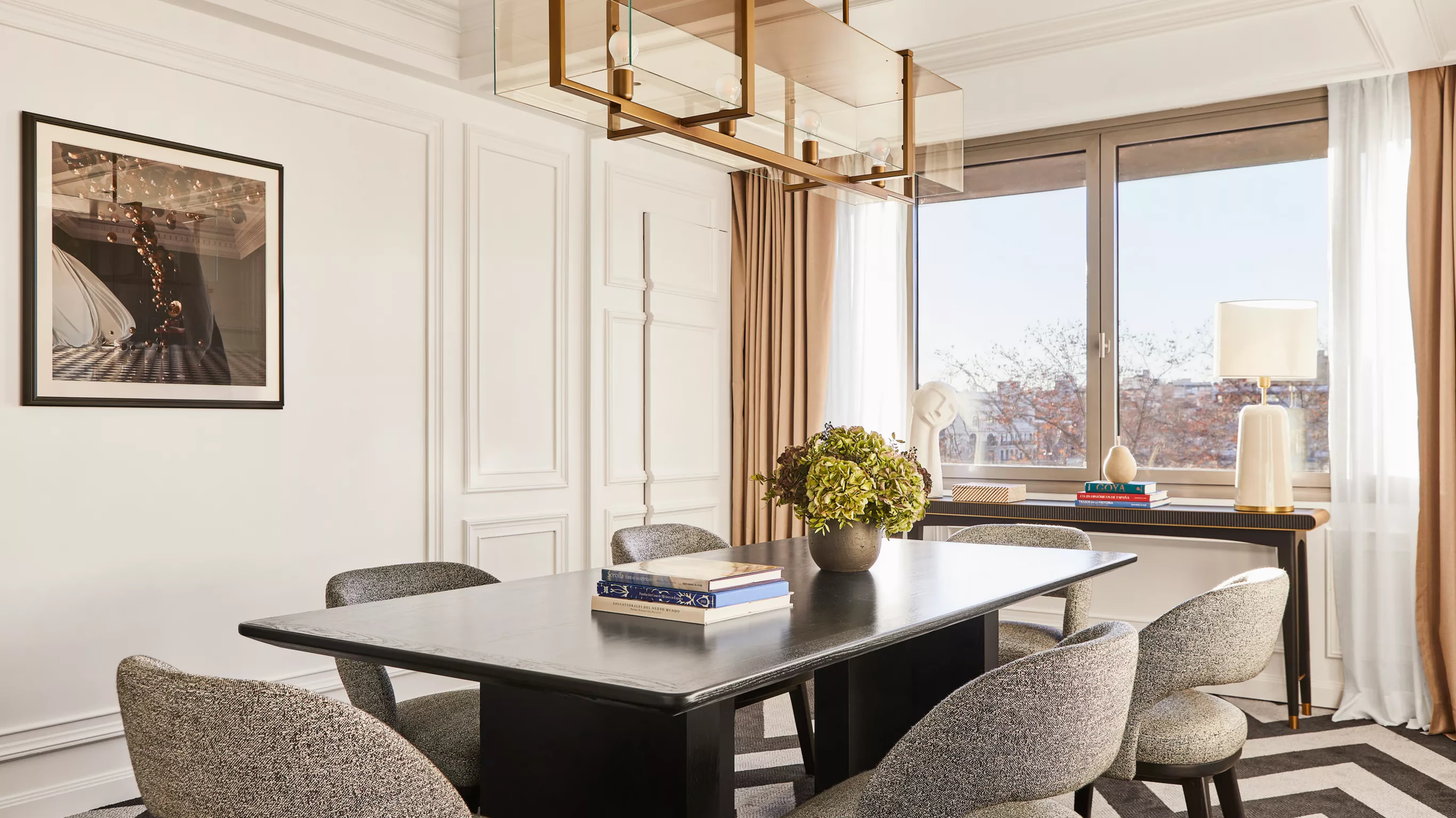 A suite with a black desk, city skyline windows, and neutral upholstery in warm tones