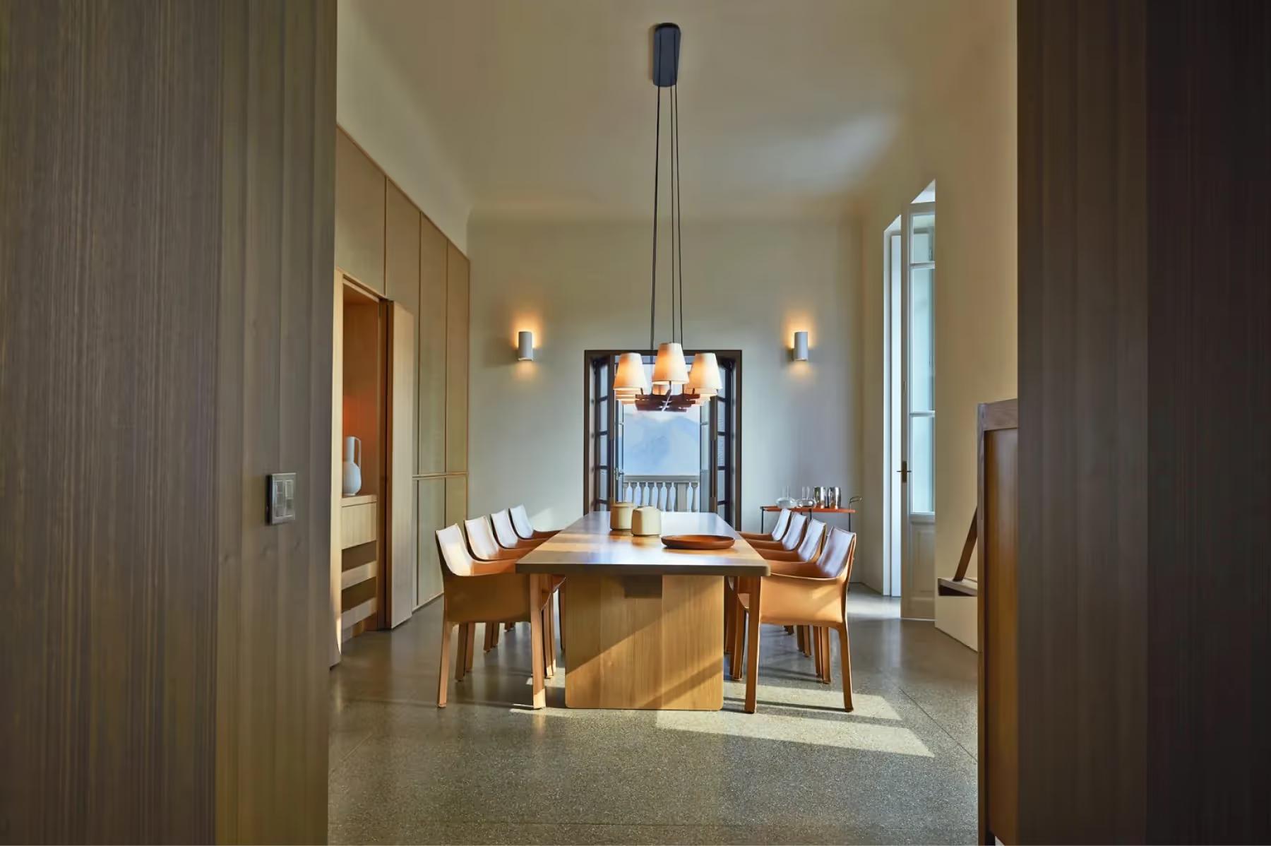 A formal dining room with wooden table, tall windows, and neutral palette