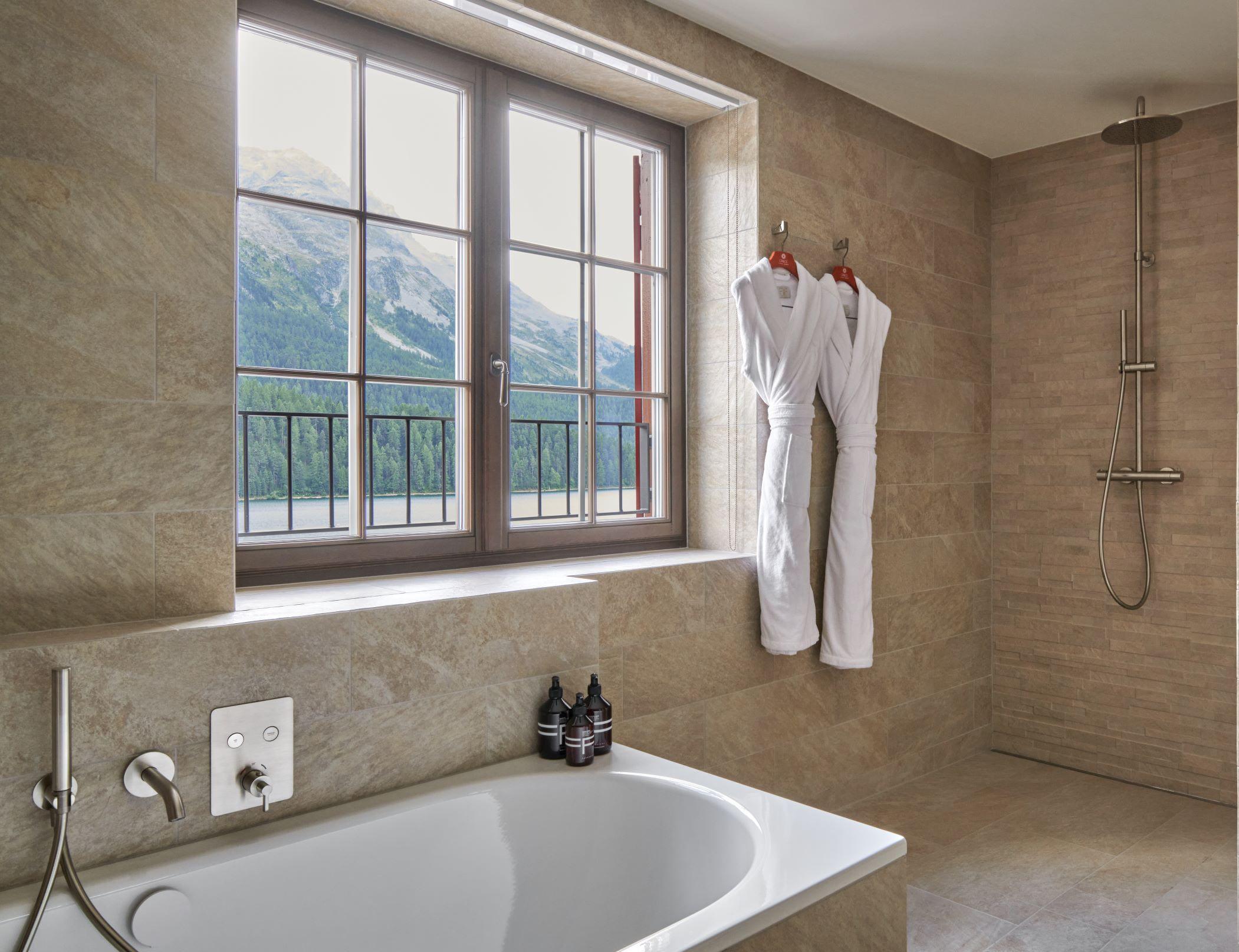 Grace La Margna St. Moritz: marble spa bathroom with stone finishes, white towels, and alpine landscape through windows