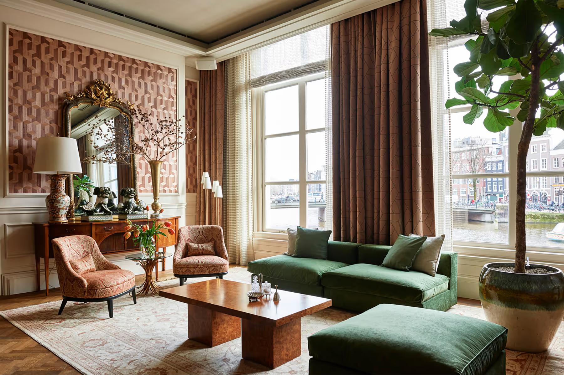 Lounge with green sofa, wooden beams, and two-story arched windows