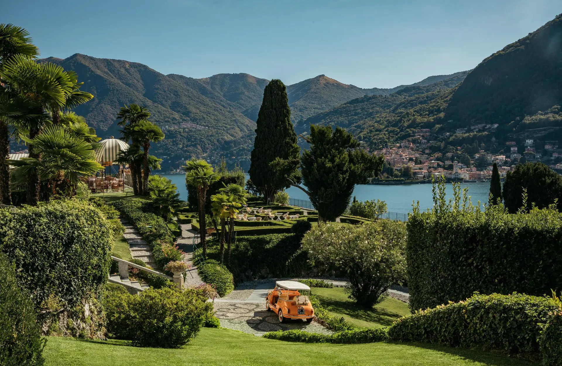 Passalacqua: terraced gardens with tall cypress, lawn furniture, and lake mountains in distance