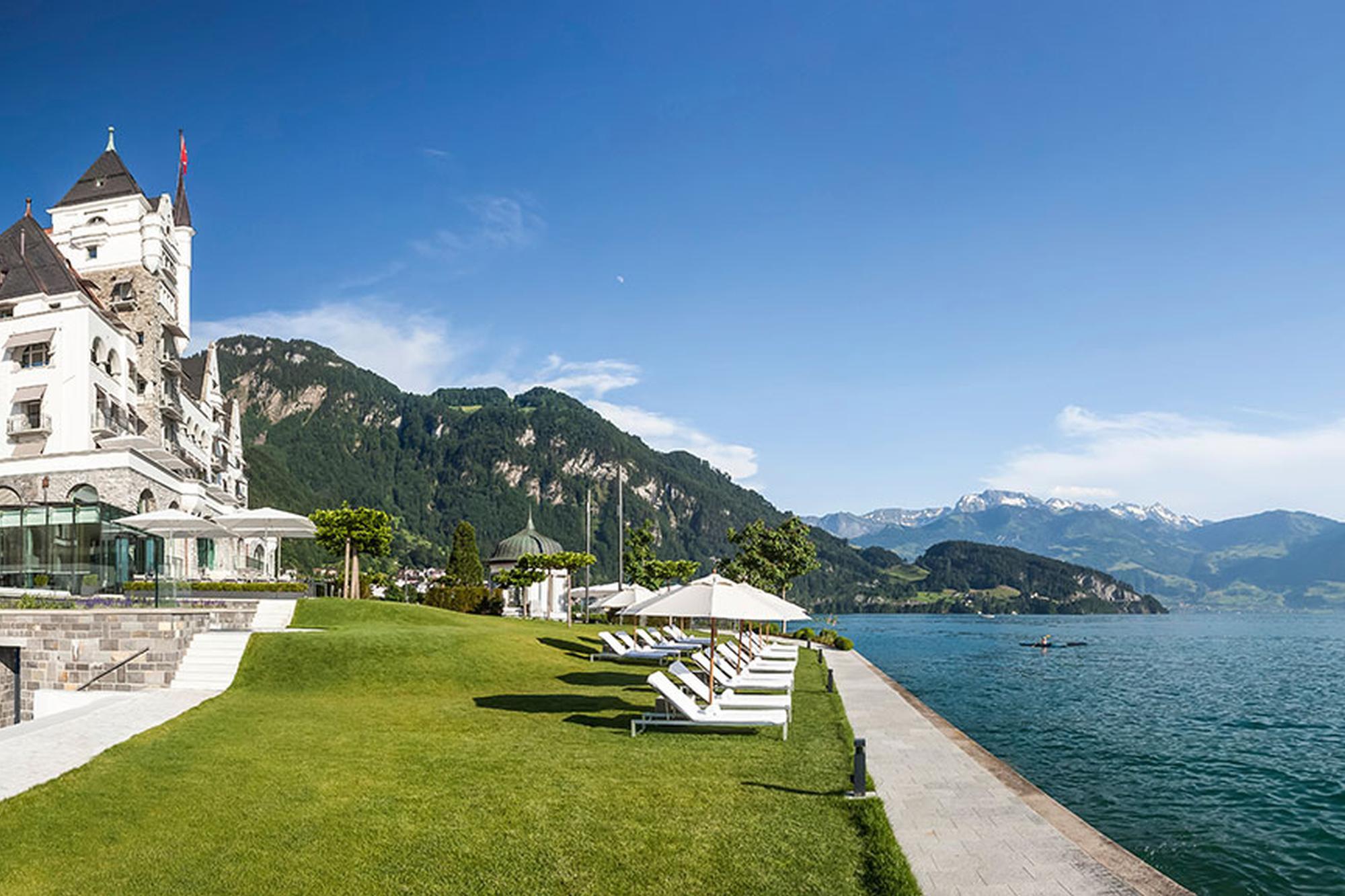 Manicured lawn beside the hotel with white lounge chairs overlooking the lake