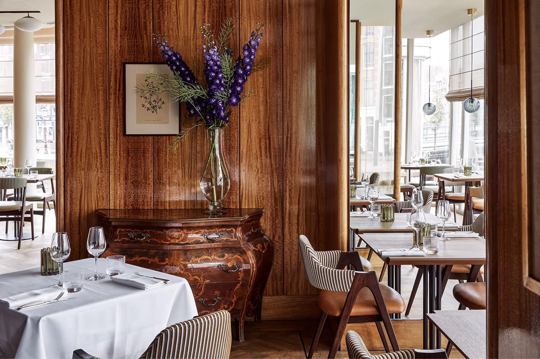 Dining area with wood-paneled walls, carved floral arrangement, and formal service setup