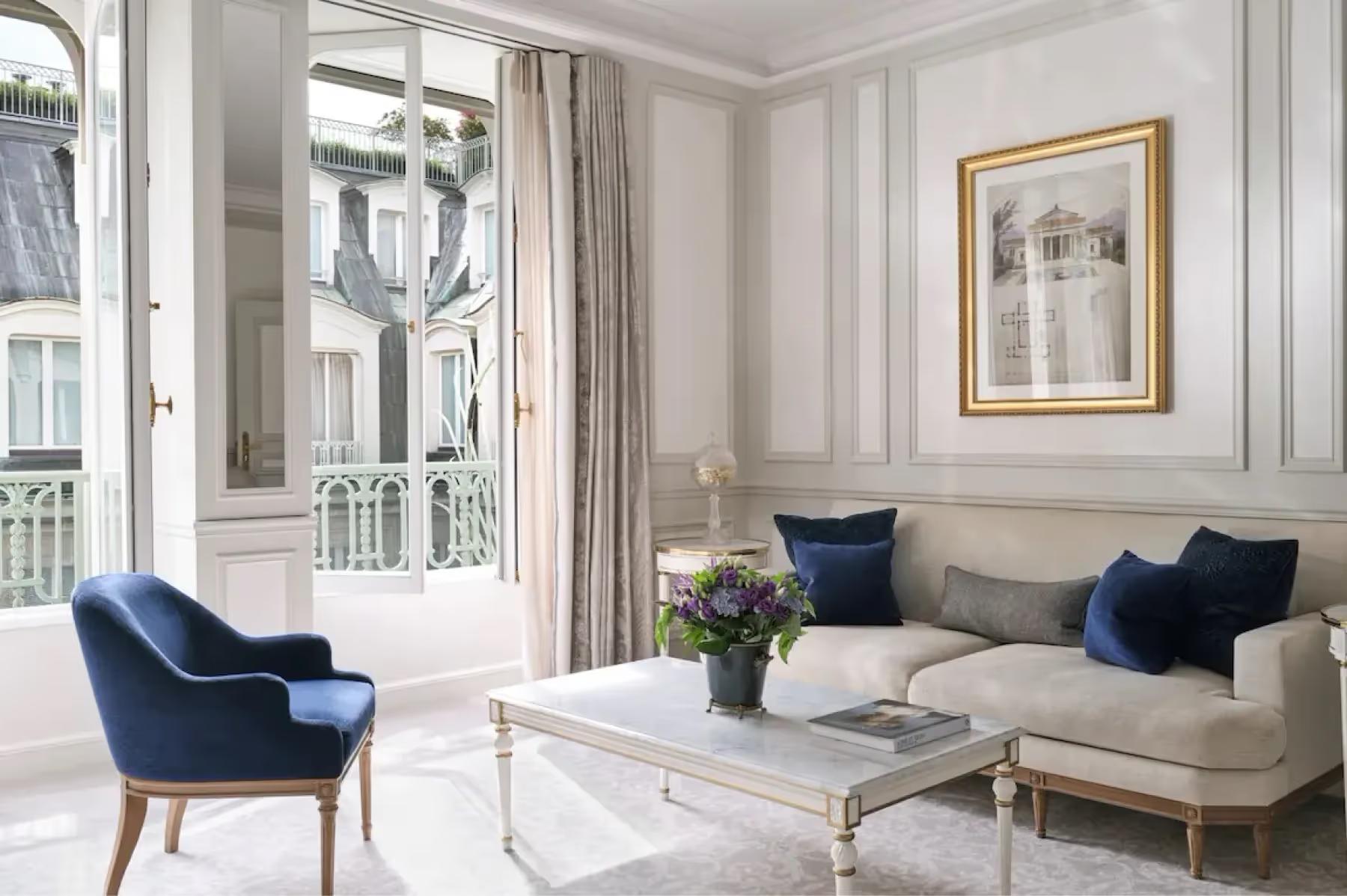 Le Meurice: a sitting area with velvet sofa and classical furnishings beside windows with floor-to-ceiling drapes