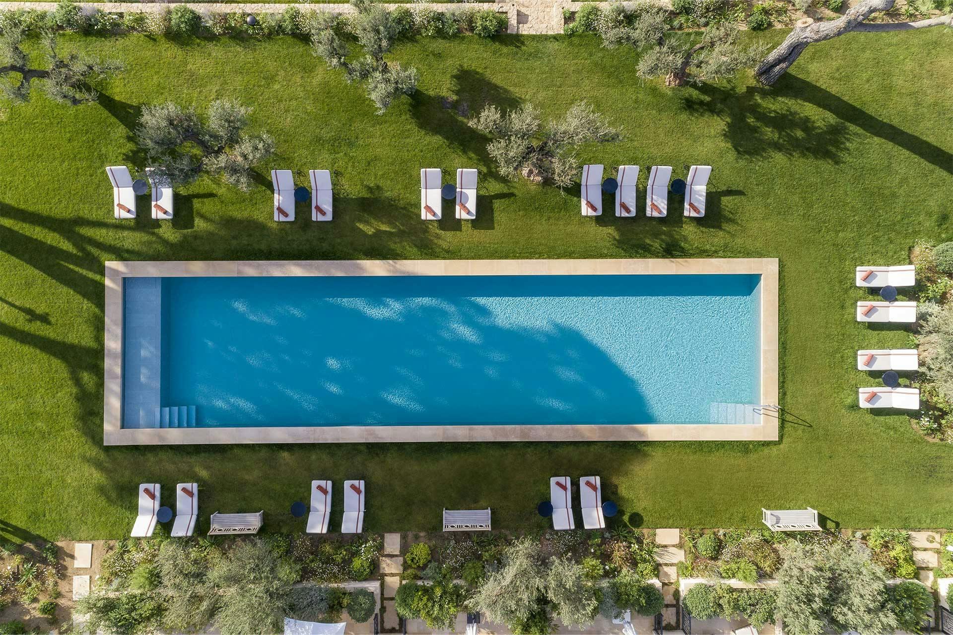 Château de La Messardière: rectangular saltwater pool surrounded by green lawn and sun loungers at midday