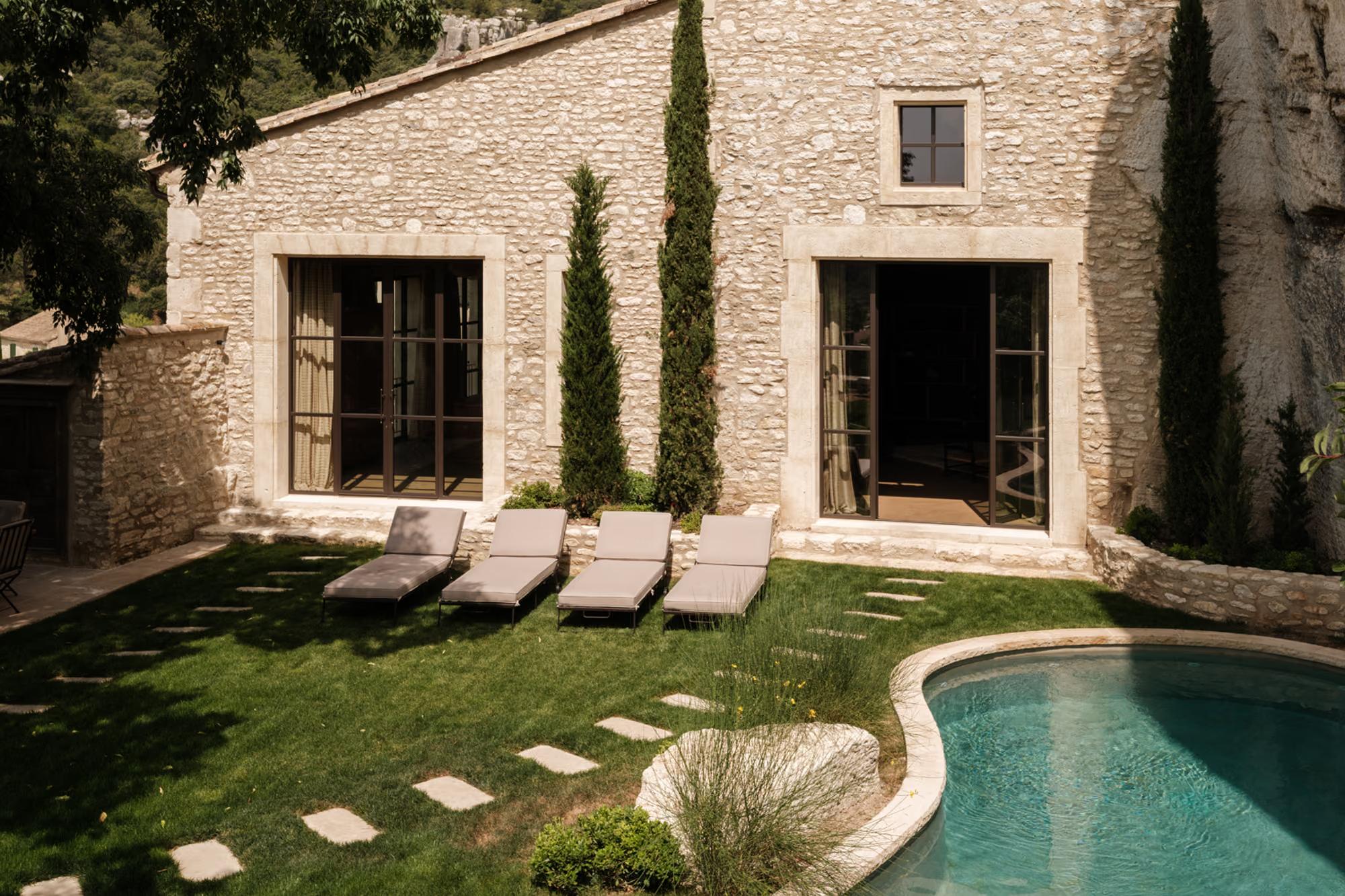 Stone facade, gravel terrace with sun loungers, aquamarine pool, white cliff backdrop