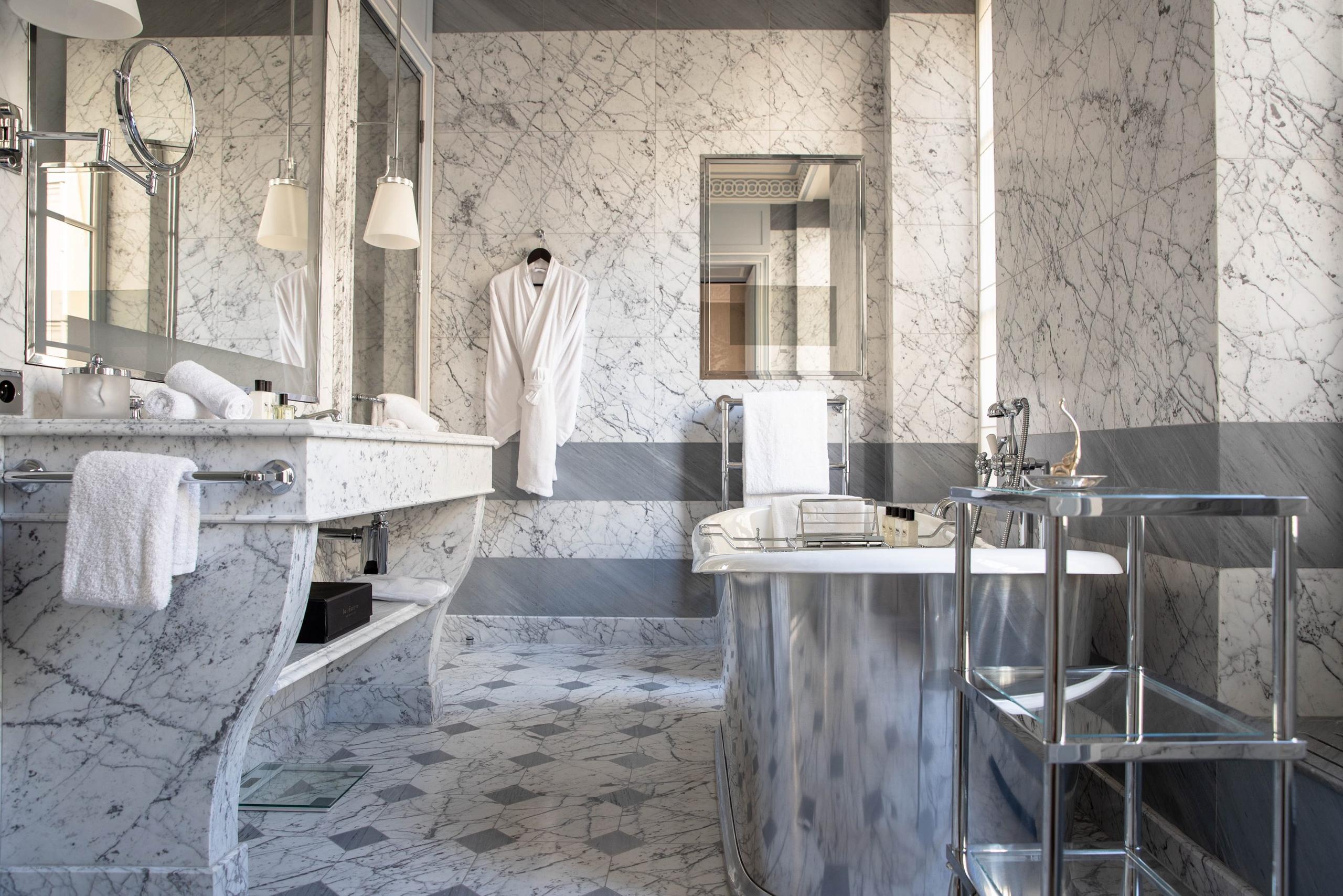La Réserve Paris: a marble bathroom with multiple mirrors, brass fixtures, and white towels