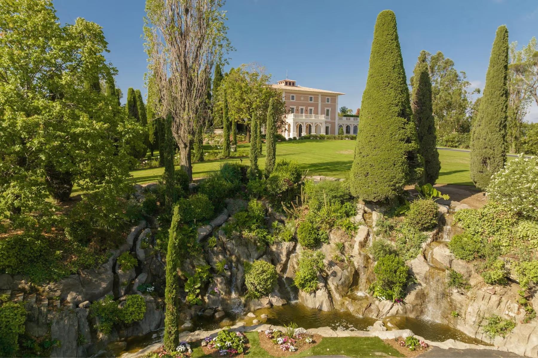 Le Château de La Croix des Gardes: garden grounds with cypress trees, ornamental urns, and distant château silhouette
