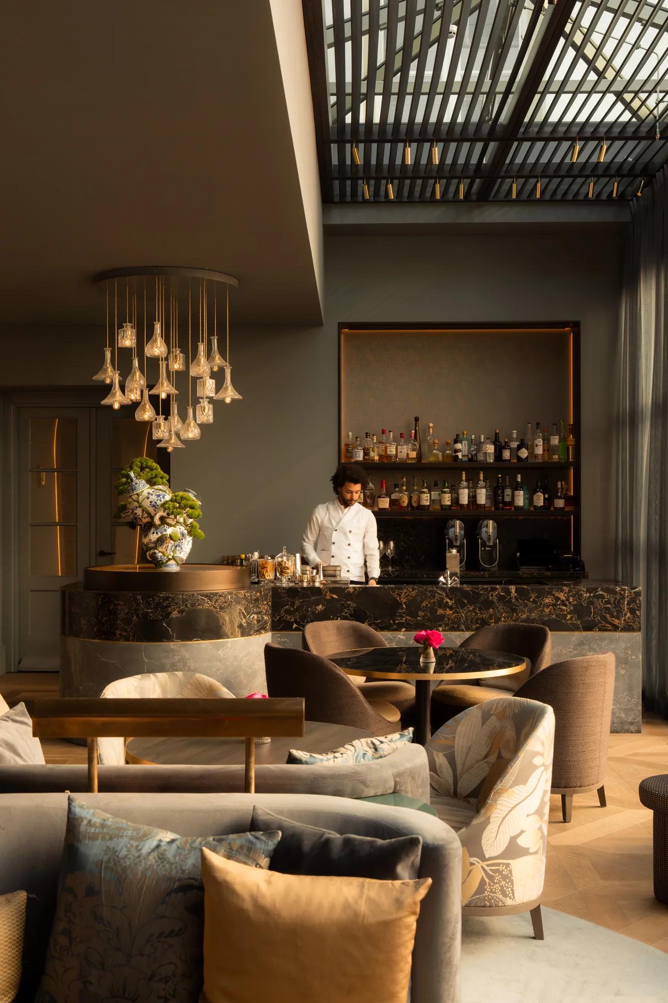 Rosewood Amsterdam: The Court lobby lounge with glass pendant lights and a marble bar