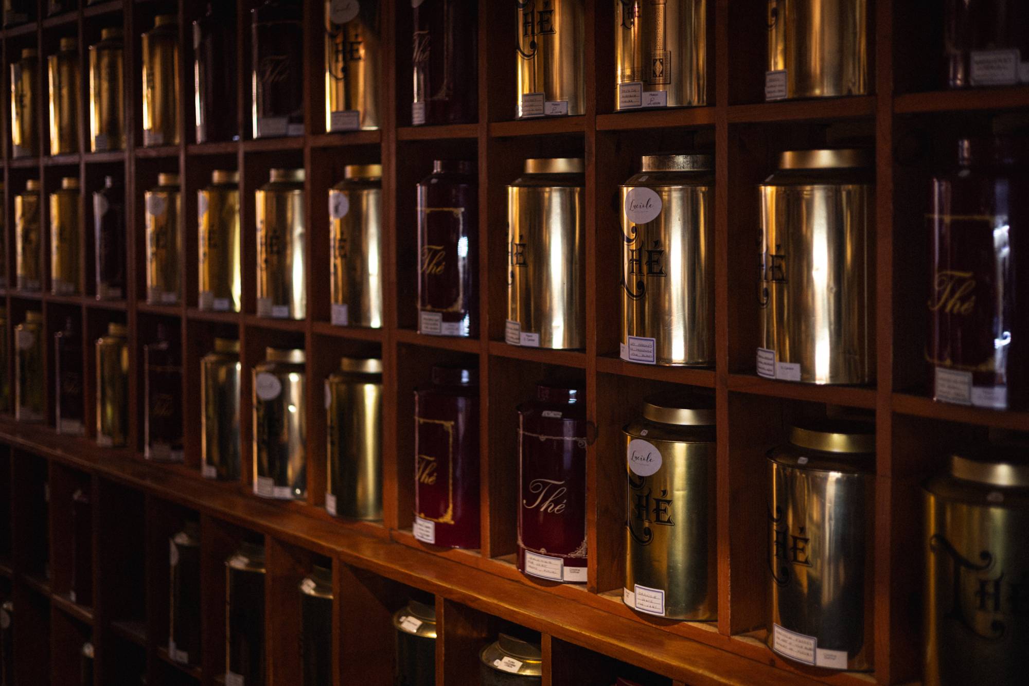 A wall of metal tea tins on dark wooden shelves at Luciole, a Japanese tea house in Marseille