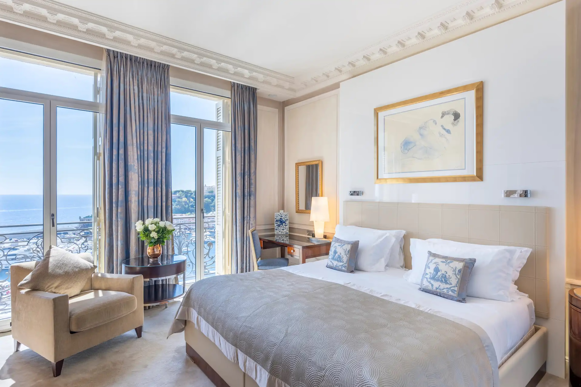 Hôtel Hermitage Monte-Carlo: master bedroom with white duvet, gold fixtures and chair seating near arched terrace