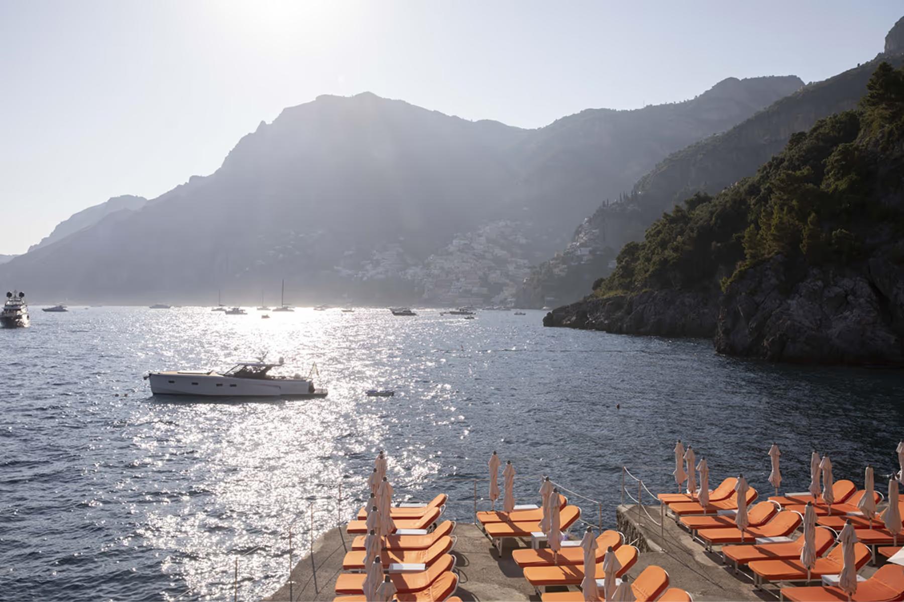 Il San Pietro di Positano: cove with striped lounge chairs overlooking sparkling Mediterranean water and distant mountains