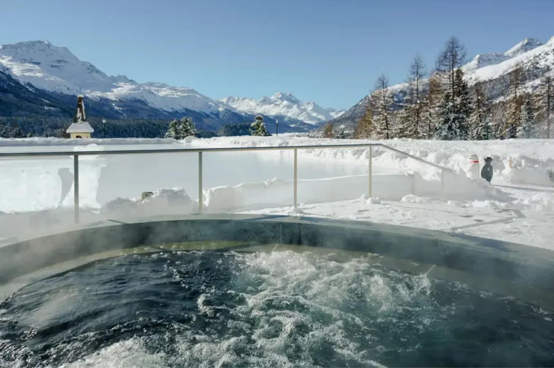 Suvretta House: an outdoor hot tub with steaming water, glass railings, and snowy alpine mountain scenery