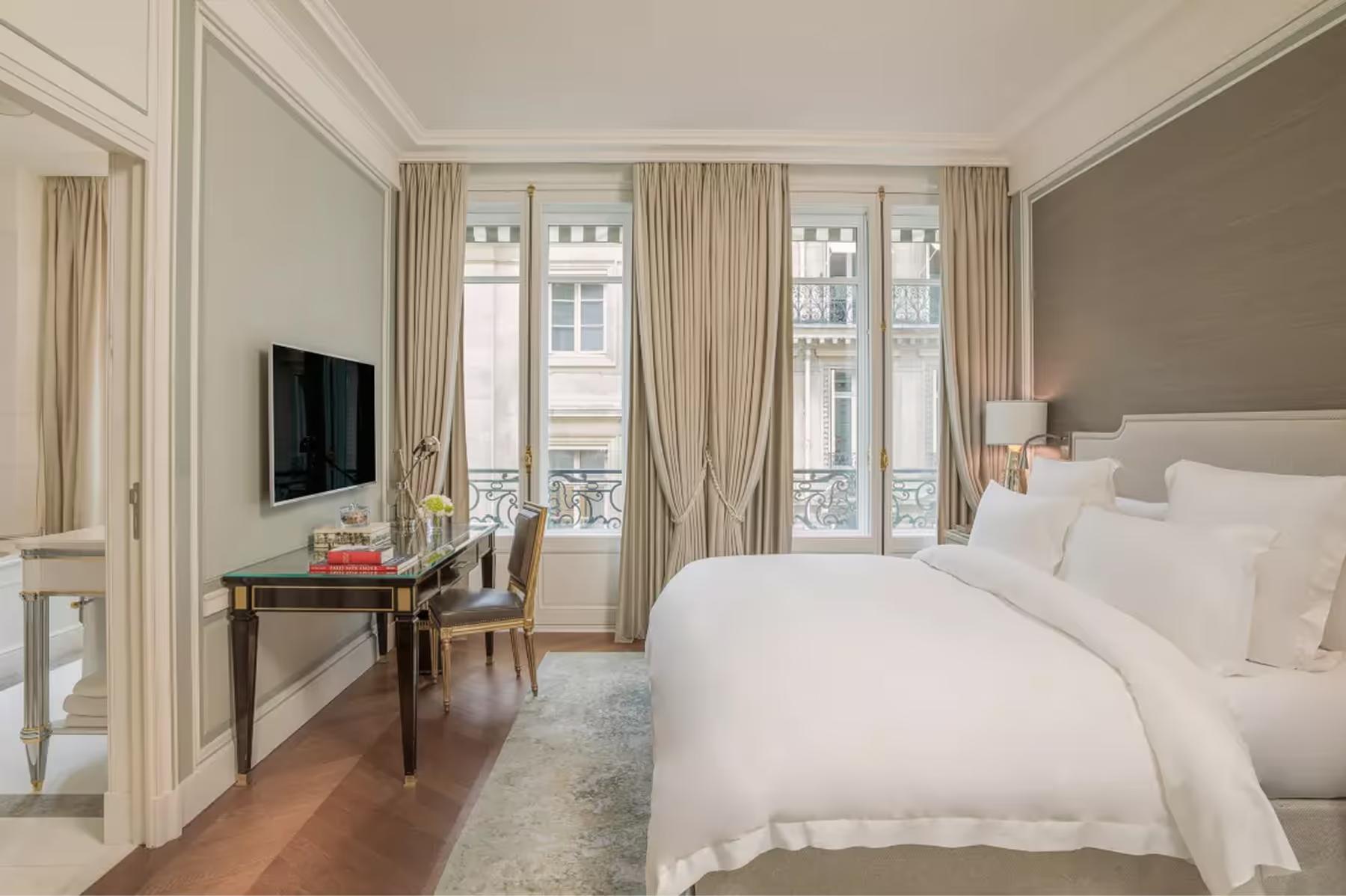 Bright room with white bed, beige walls, tall windows, and hardwood floors