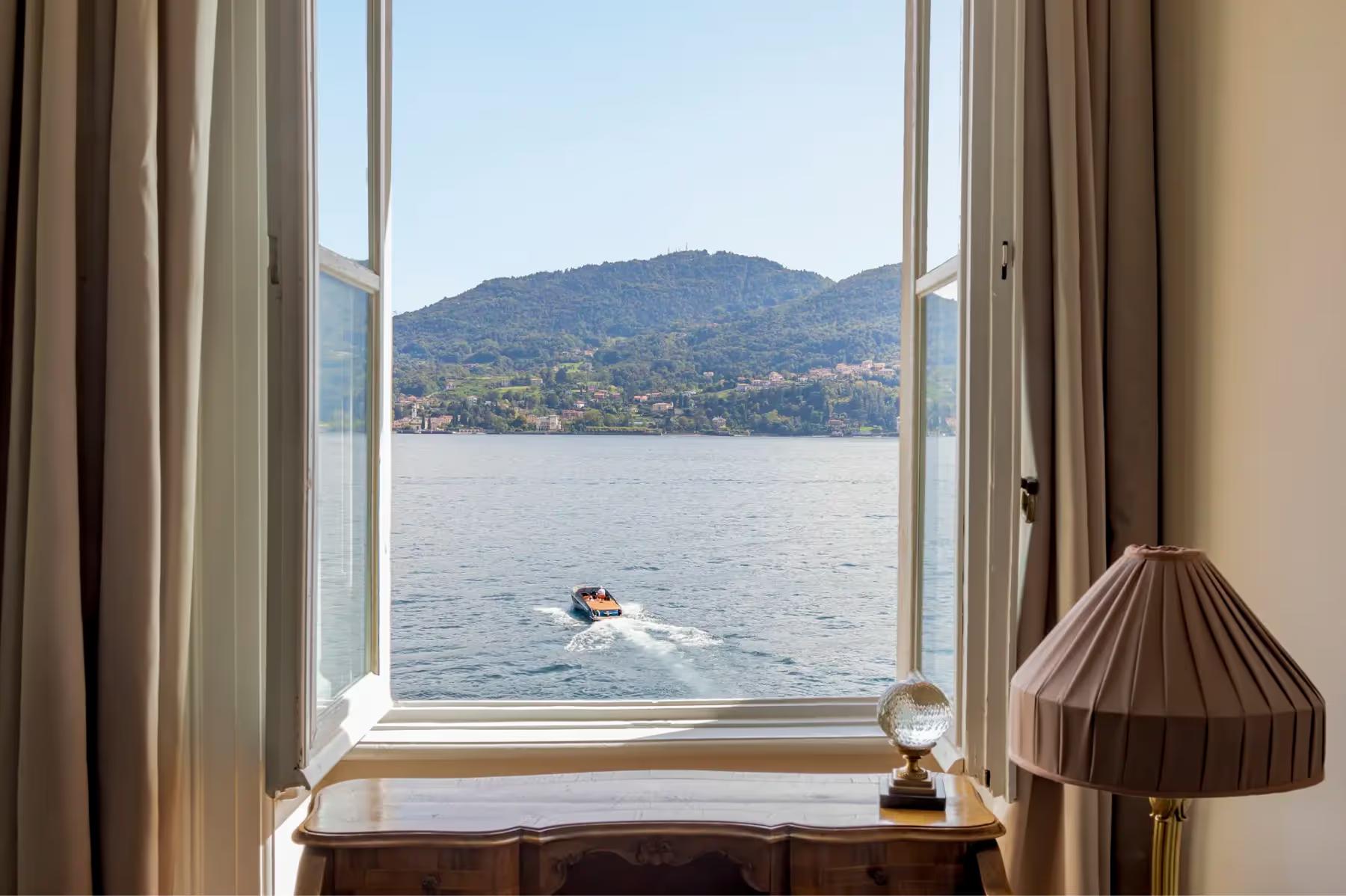 Lake Como view from a suite window with a small lamp on the sill