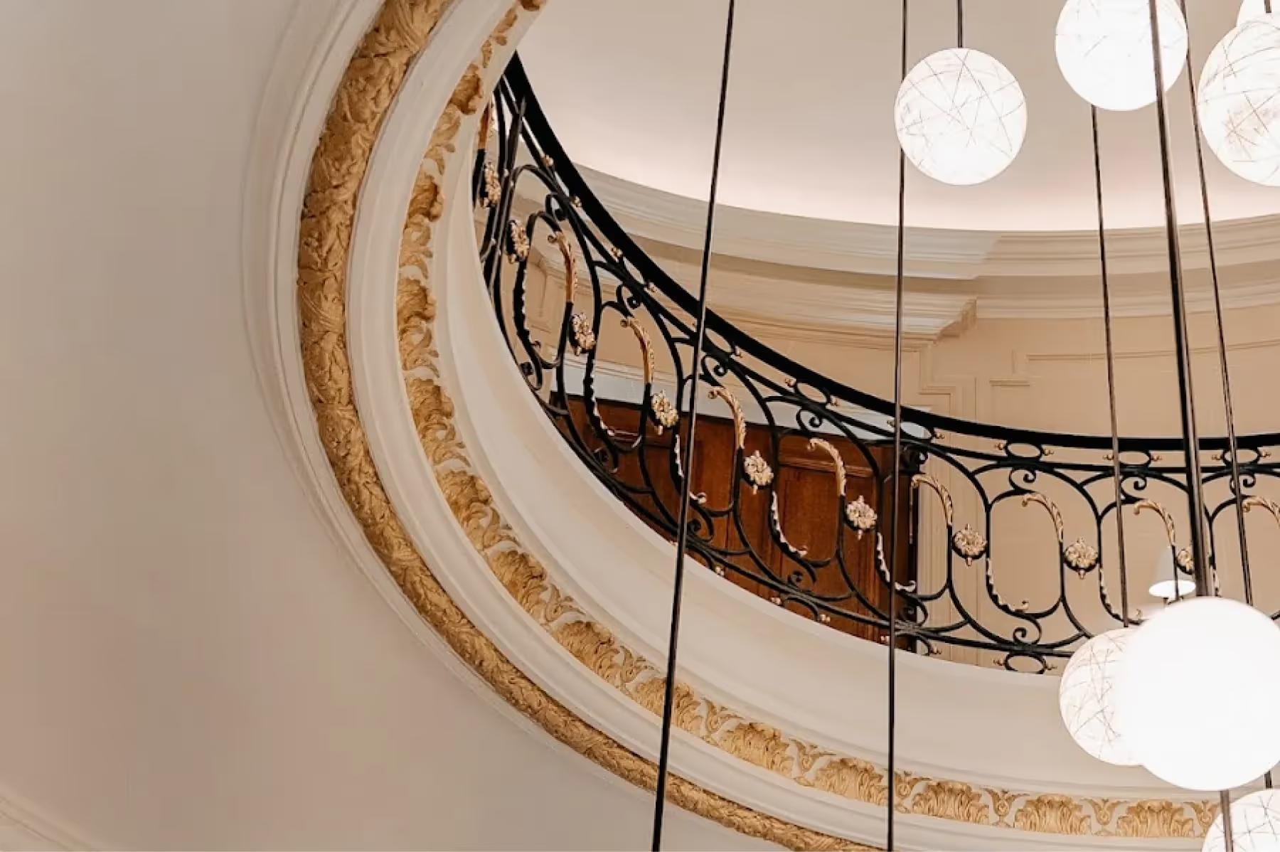 Maison Villeroy: a view looking up at a spiral staircase with ornamental railings and pendant lights