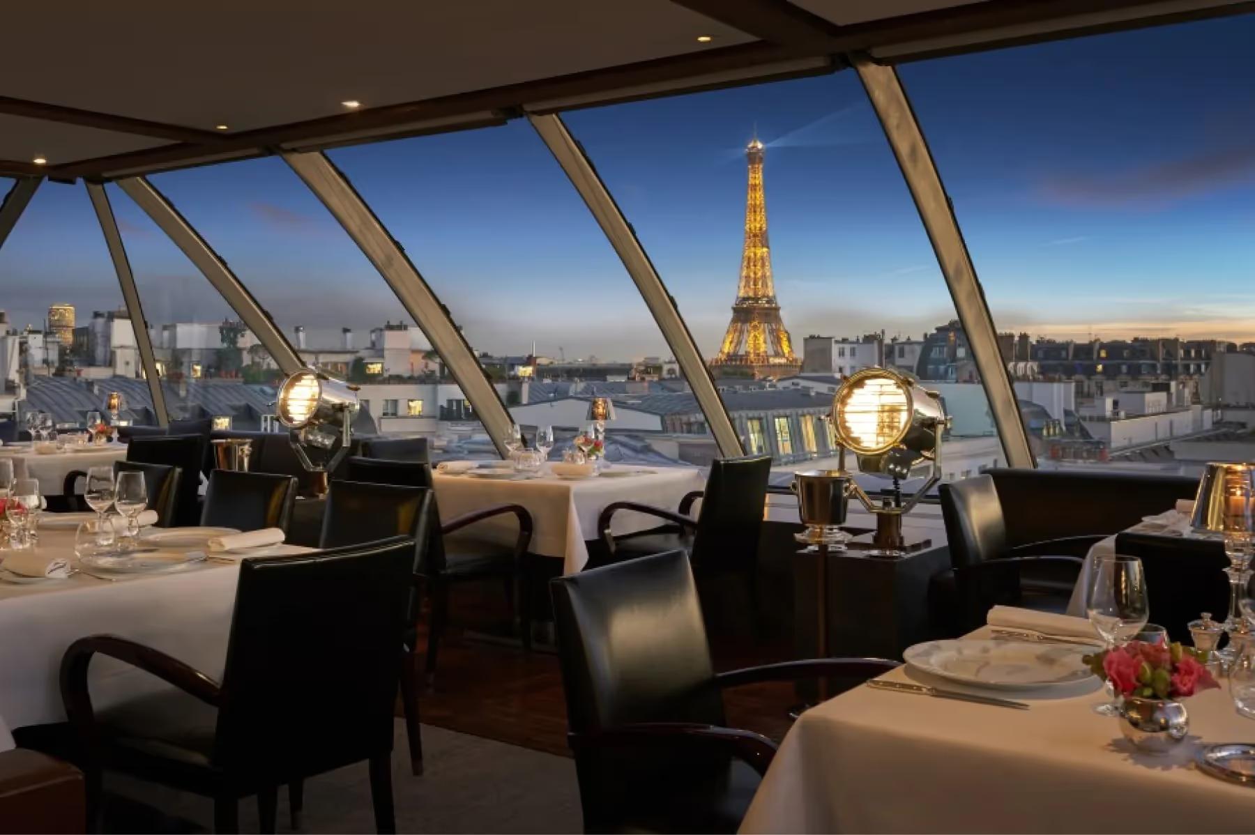 The Peninsula: rooftop terrace at night with candles, white linens, and Paris cityscape including the Eiffel Tower