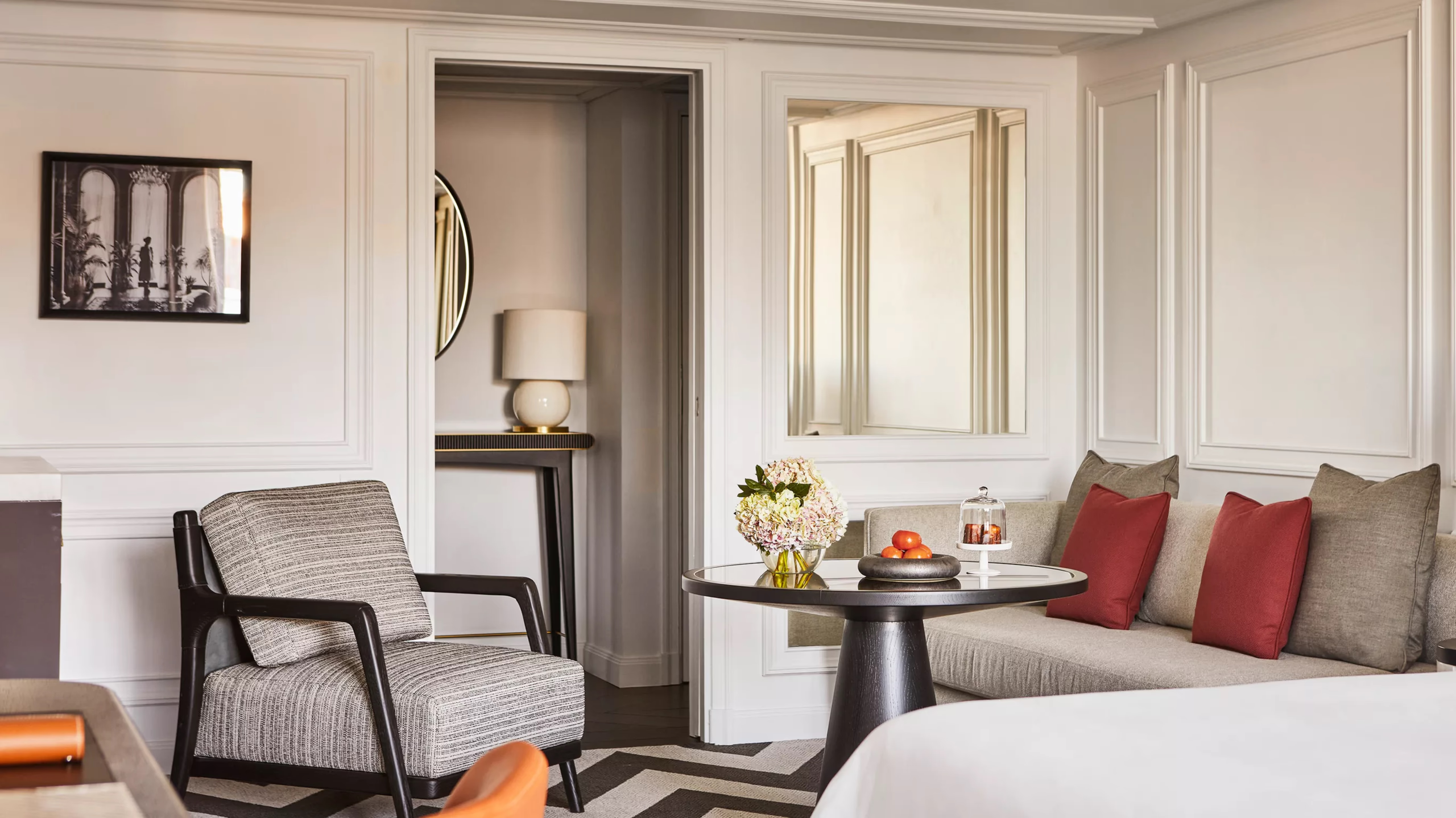 Rosewood Villa Magna: a suite sitting area with accent chairs, marble fireplace, and bedroom beyond