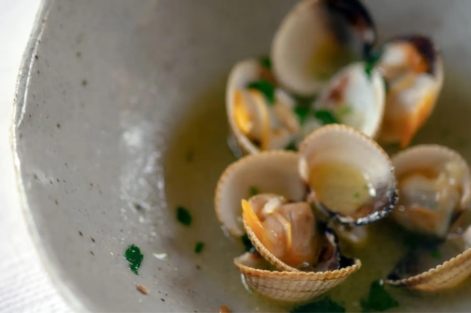 Es Racó d’Artà: plated appetizer of clams in broth garnished with herbs in white ceramic bowl