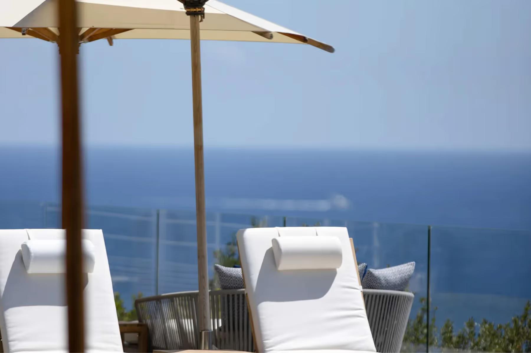 La Réserve Ramatuelle: two white lounges beneath a wooden umbrella with Mediterranean horizon