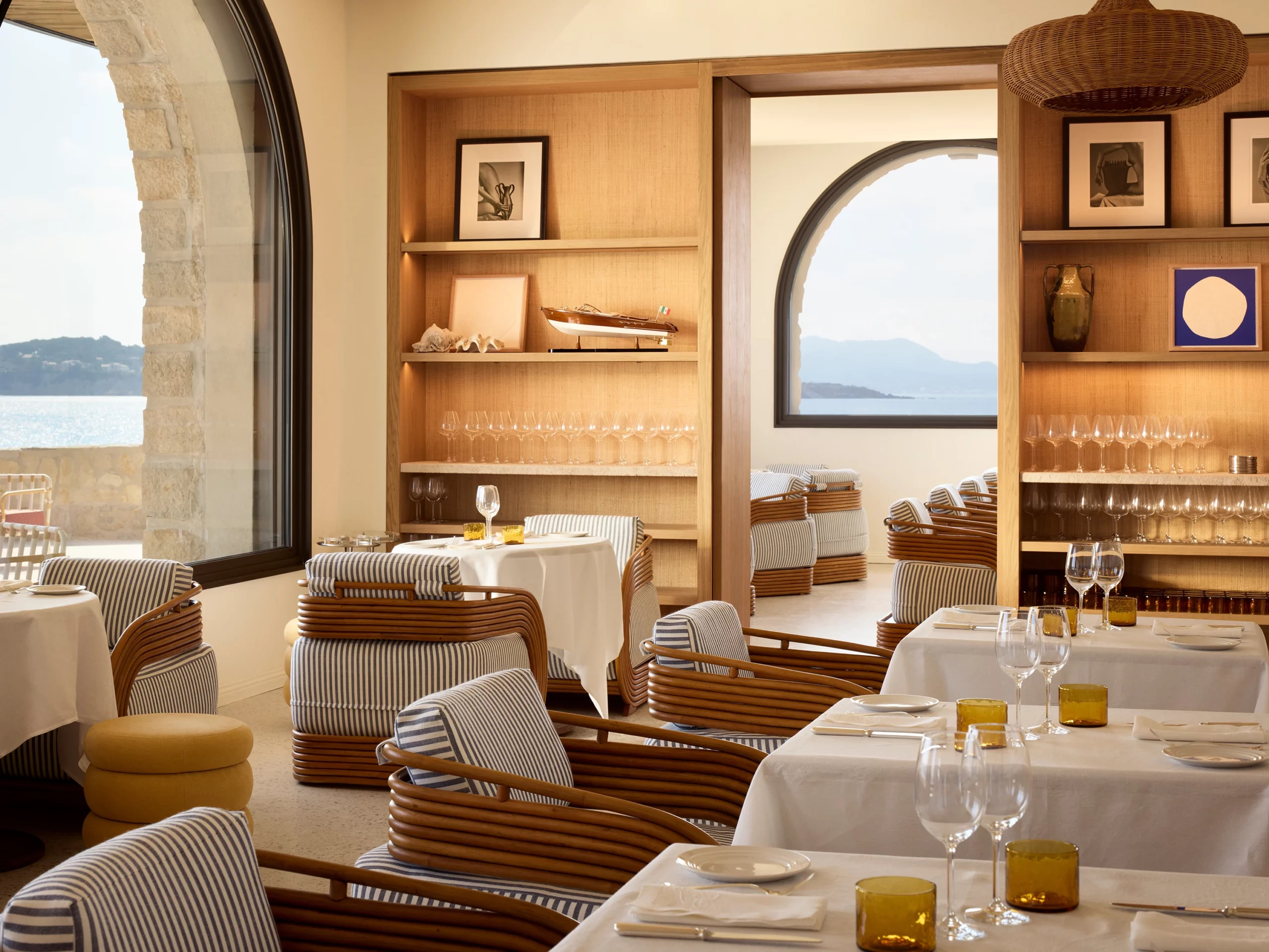 Zannier Île de Bendor: dining room shelves hold curios and glassware between stone arches framing the sea