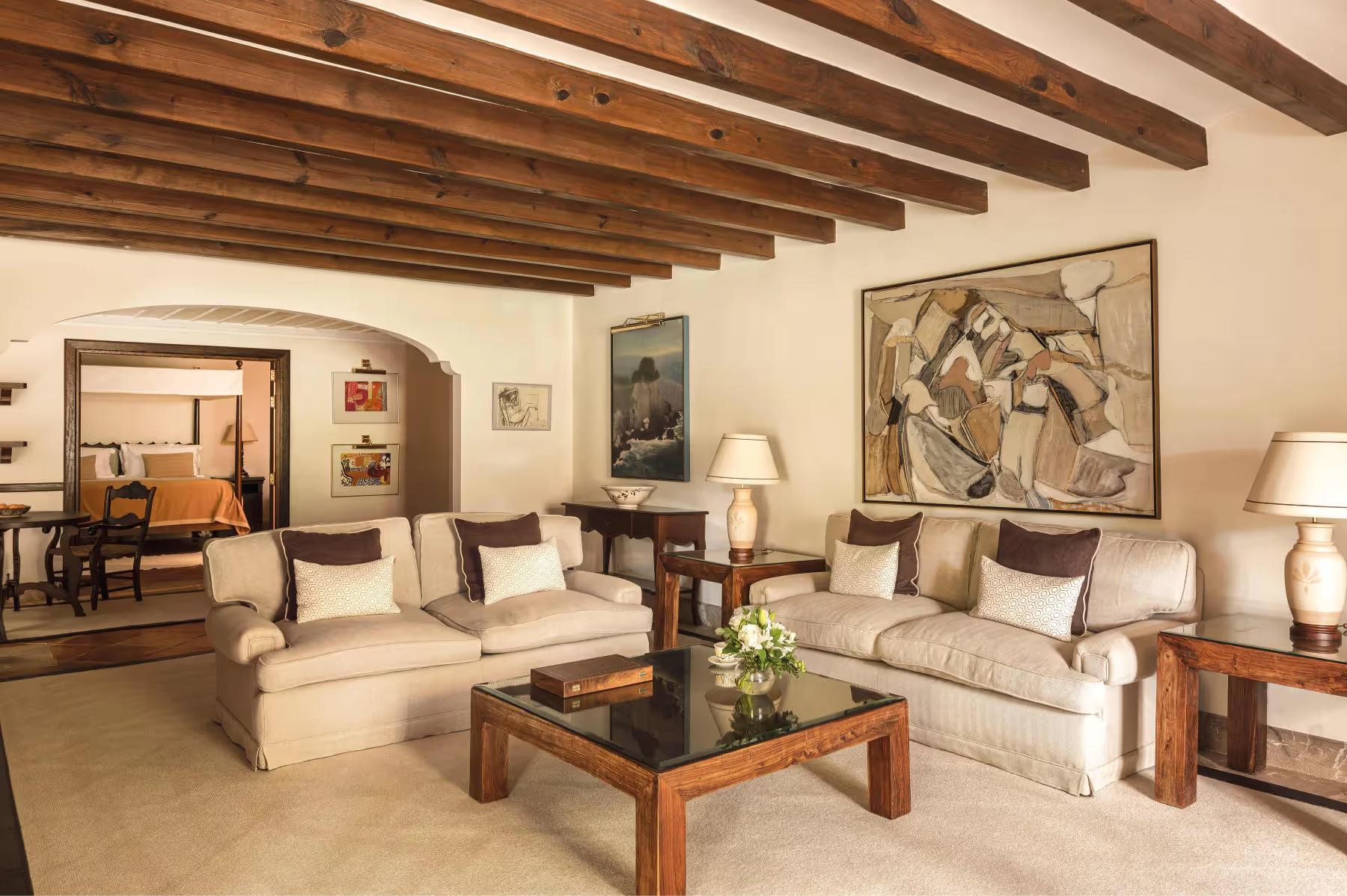 La Residencia: living room suite with beamed ceiling, sectional sofa, coffee table, and terracotta tile floor