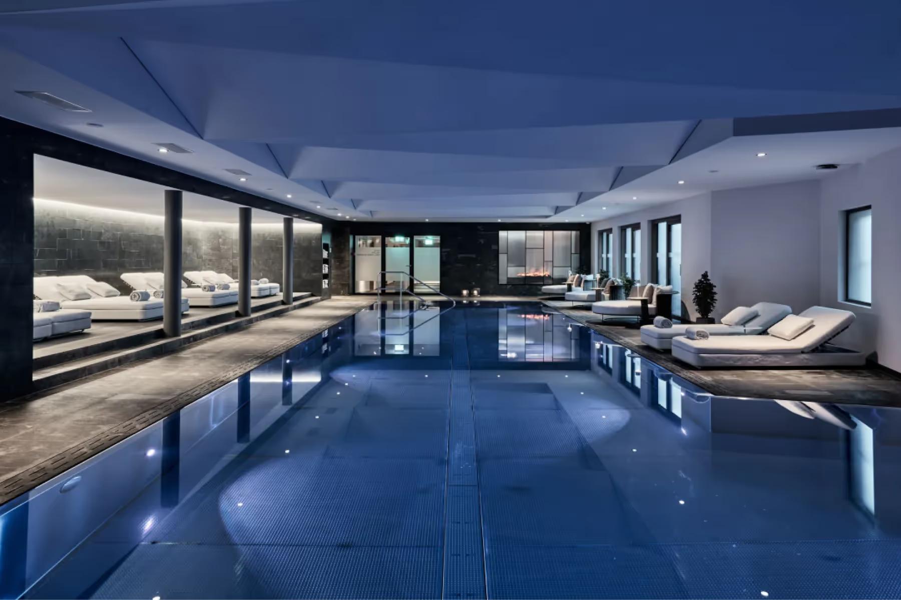 Grace La Margna St. Moritz: large indoor pool with glass ceiling, loungers, and sweeping alpine mountain views