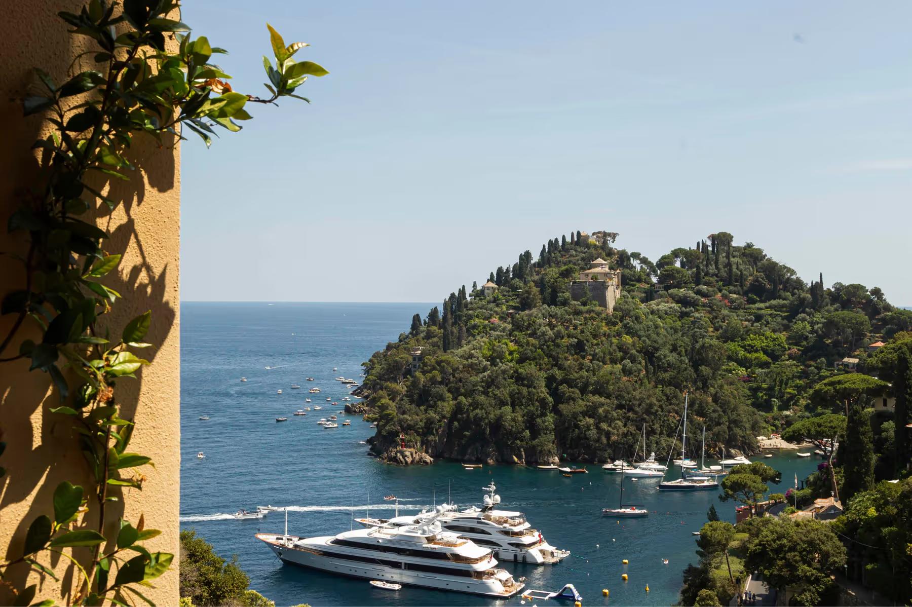 Splendido: an oceanfront hotel cove with sailboats and tropical vegetation cascading to the water