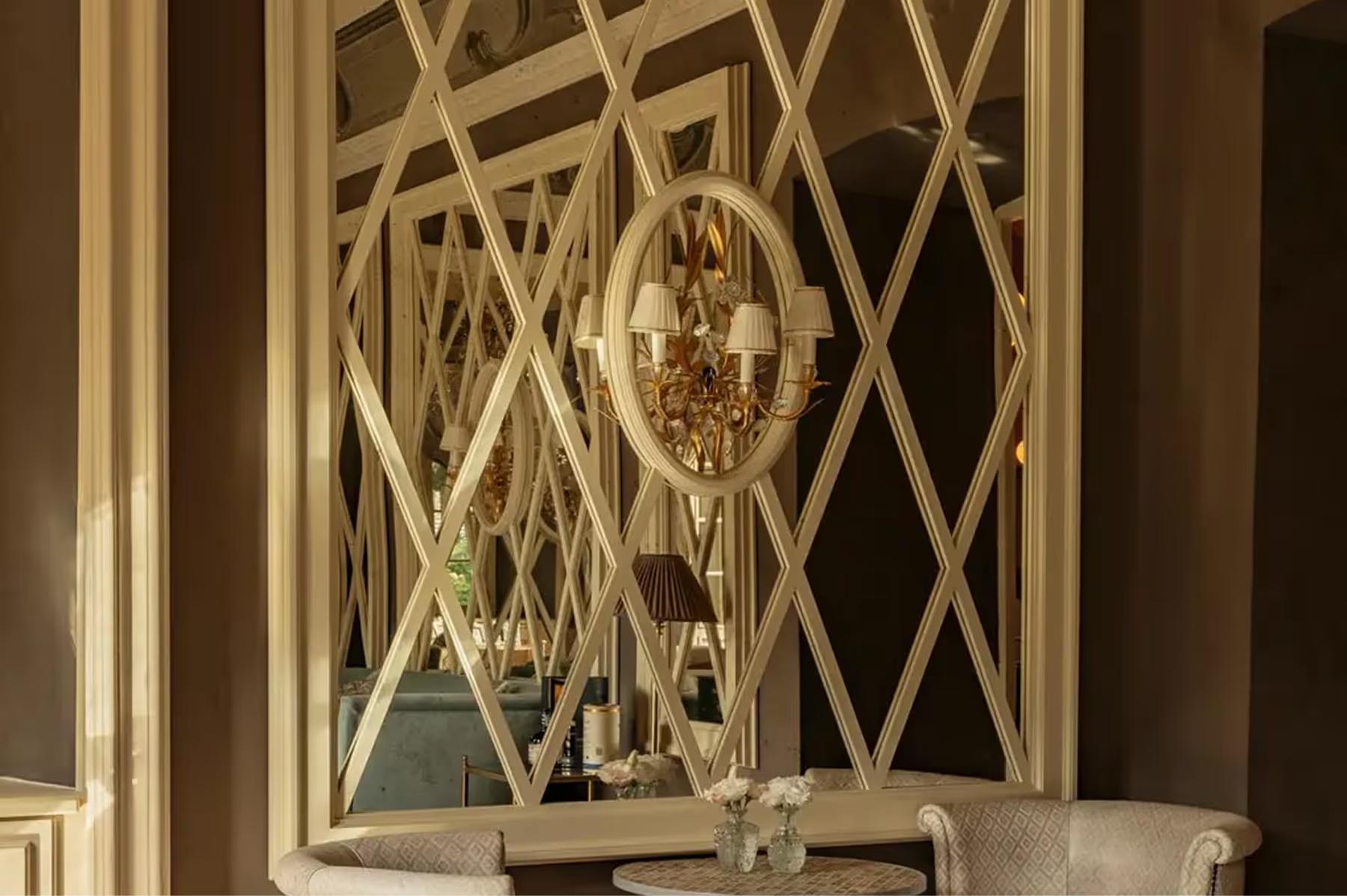 Passalacqua: an ornate gold-framed mirror flanked by cream panels with geometric wallpaper