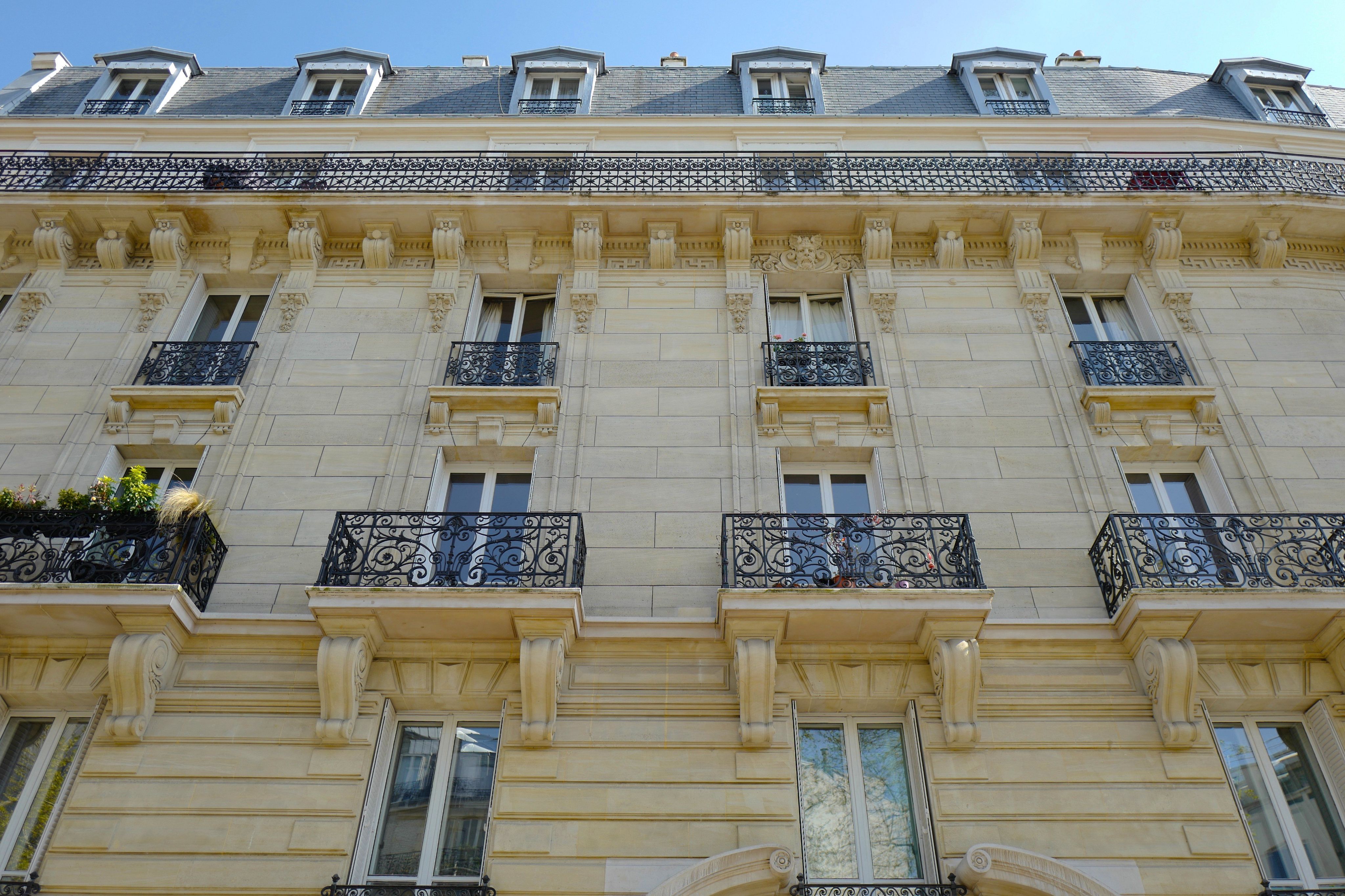 The pale stone facade and wrought-iron balconies of a Haussmann-style building on Rue Paradis in Marseille