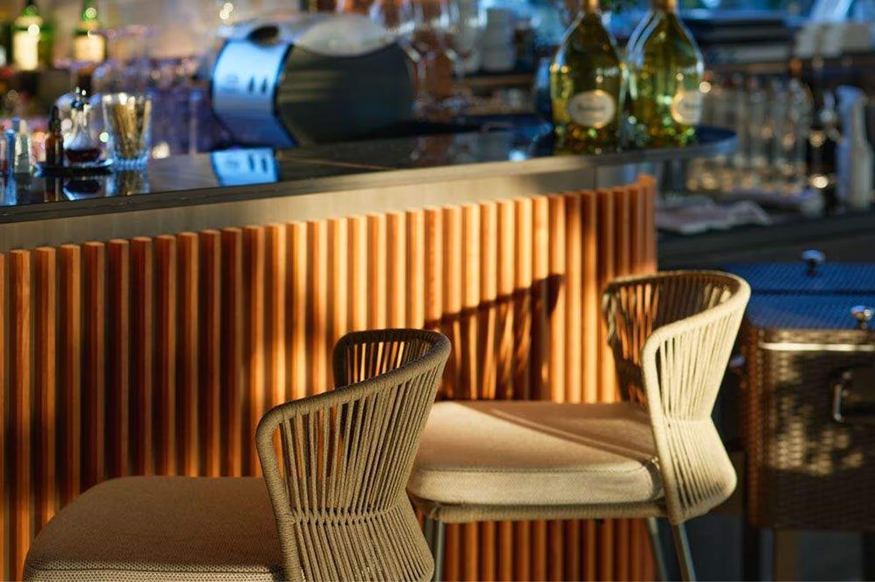 Bar seating with brass railings and glassware in soft lighting