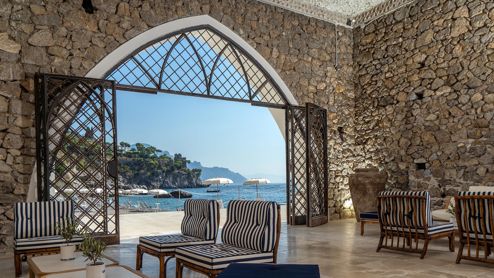 Borgo Santandrea: dining room with arched stone walls and sea views through latticed window opening