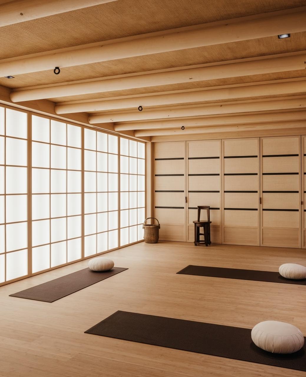 Aman Le Mélézin: yoga studio with shoji screen walls, timber beam ceiling, and mats set out for practice