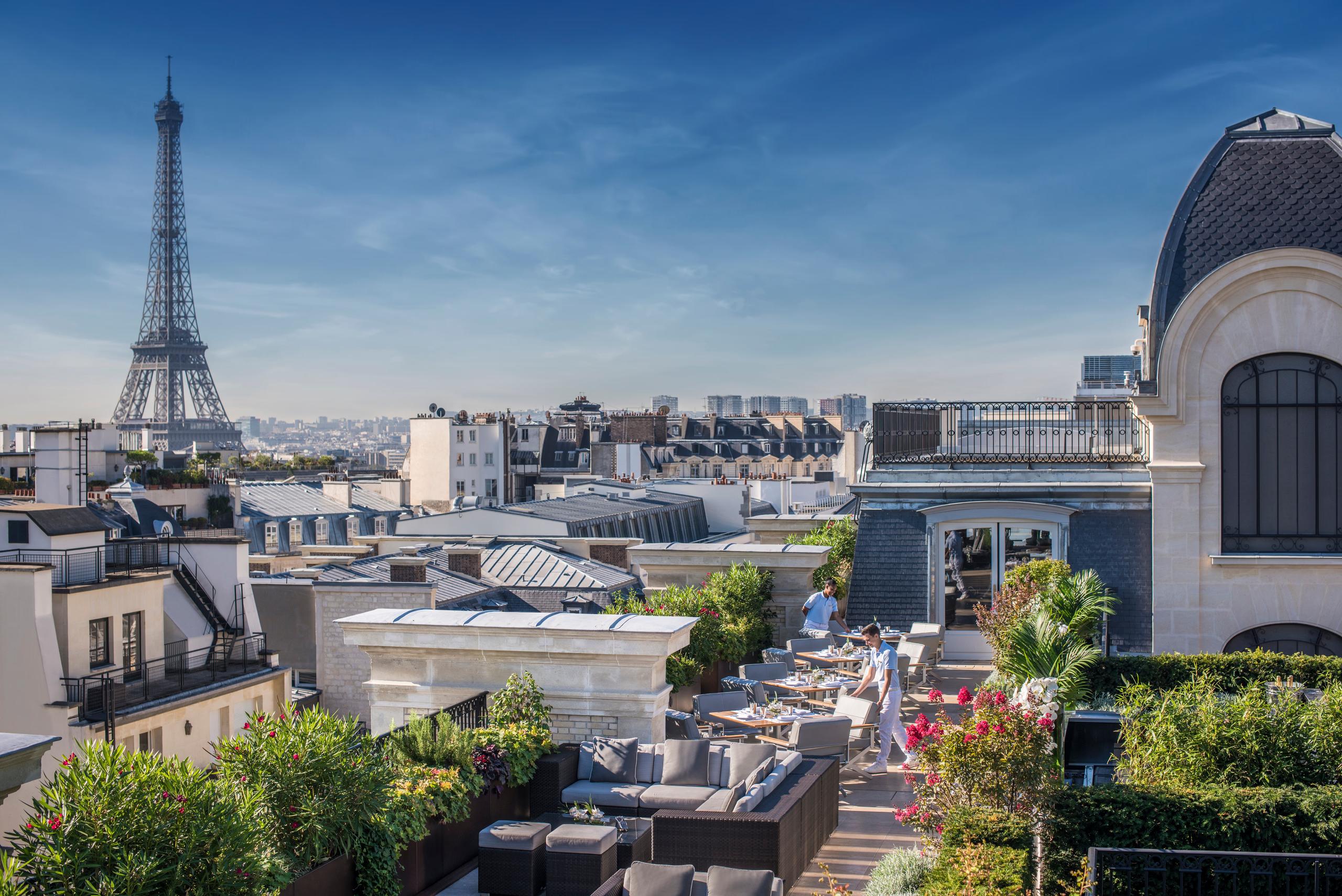 The Peninsula: rooftop terrace with white stone columns, potted plants, and dining tables overlooking Paris