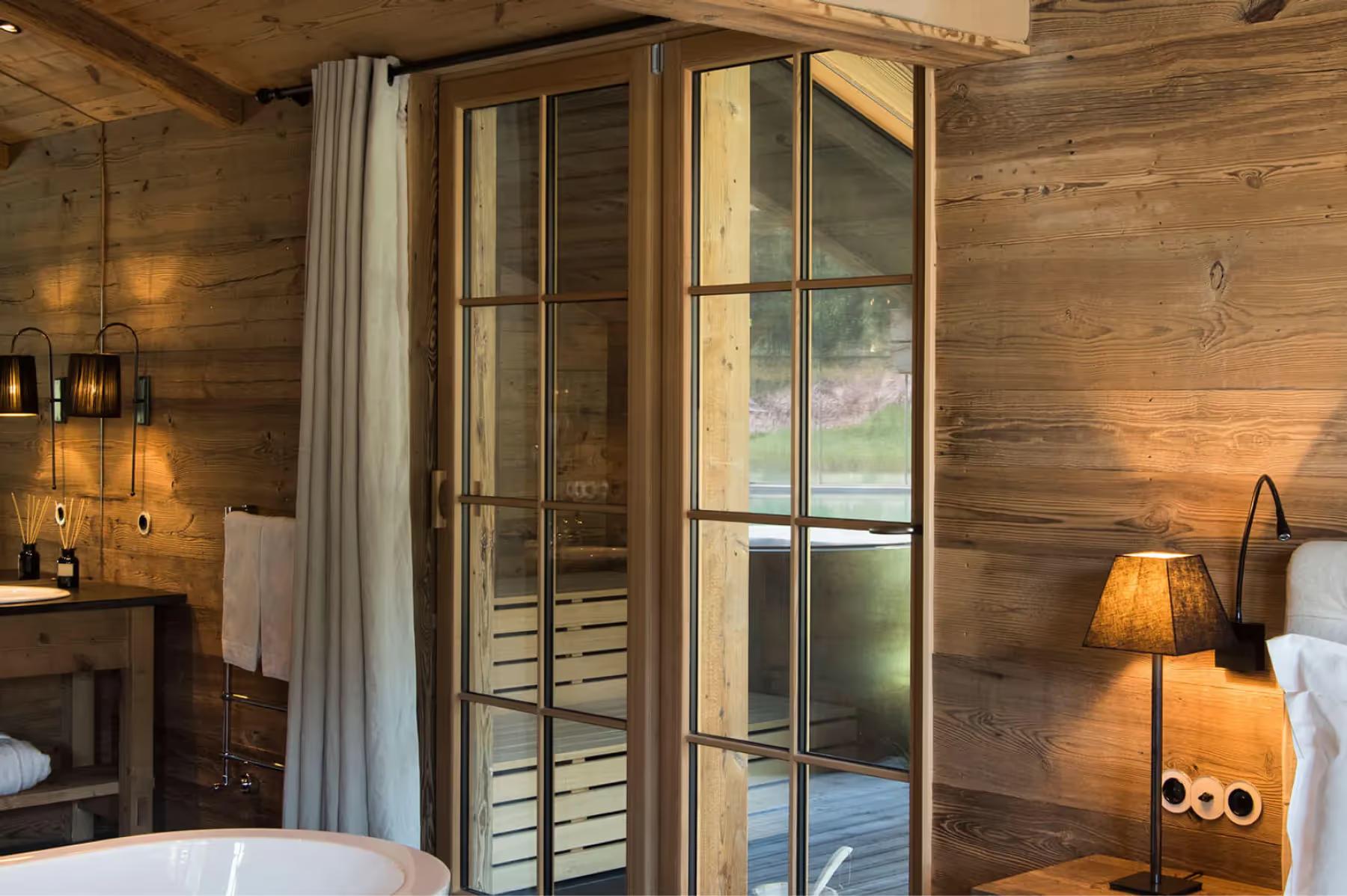 San Luis Retreat: wood-lined bedroom with glass partition walls and a freestanding tub
