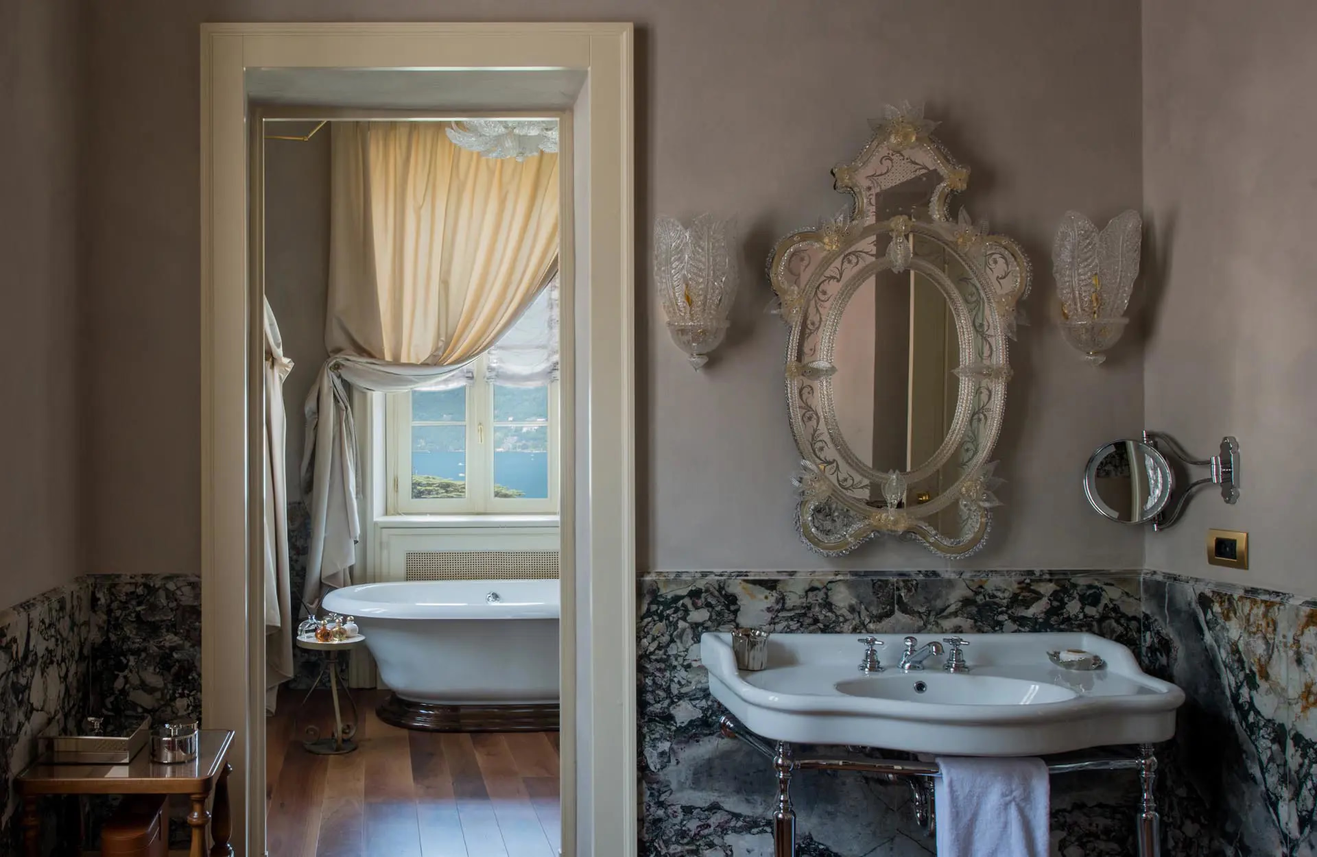 Passalacqua: a bathroom viewed through an arched doorway with ornate sink and mirror