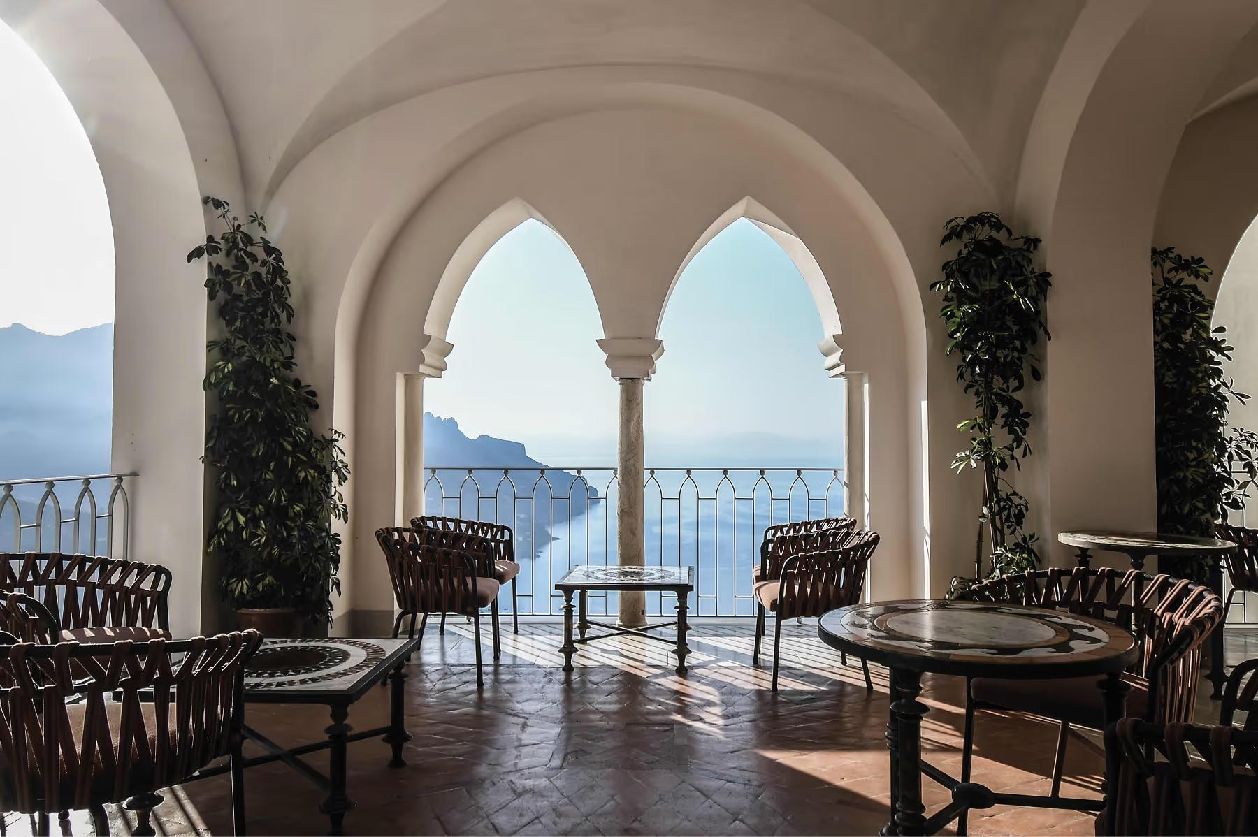Caruso: arcade pavilion with ornate columns, stone seating, painted ceiling panels, and panoramic coastal view