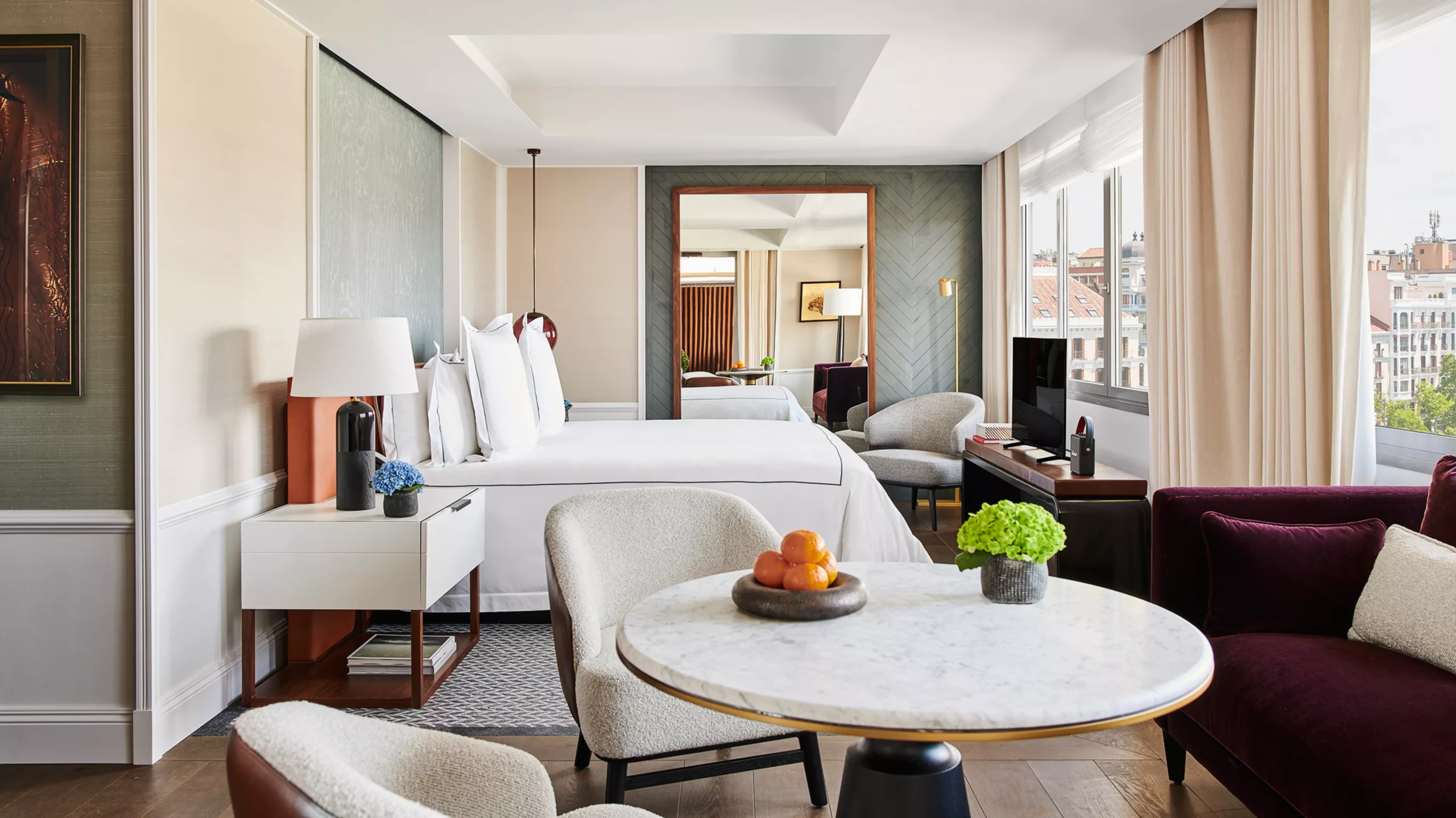 Rosewood Villa Magna: a suite with white bedding, sitting area, and glass partition separating the living space