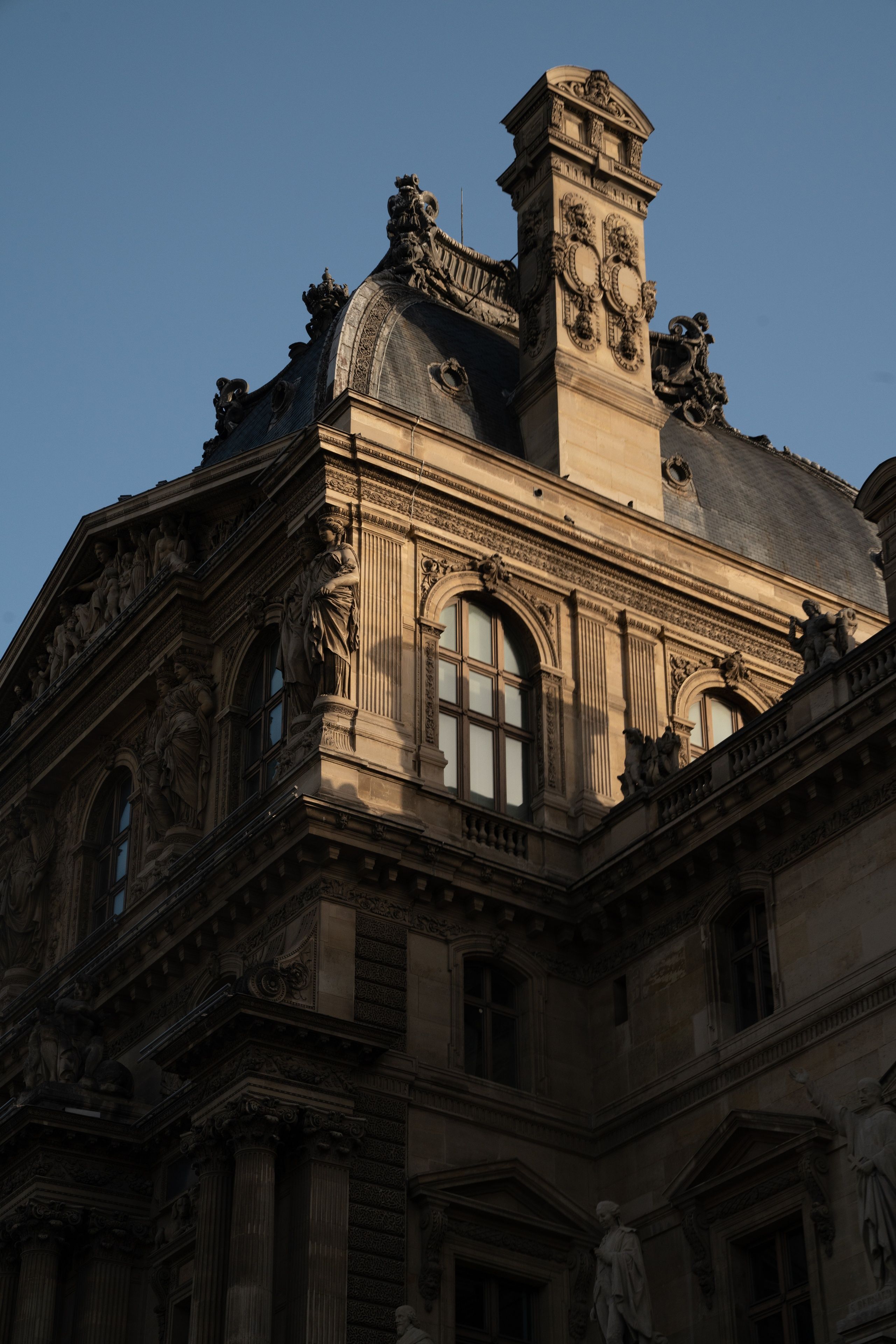 The ornate stone roofline of the Louvre in evening light
