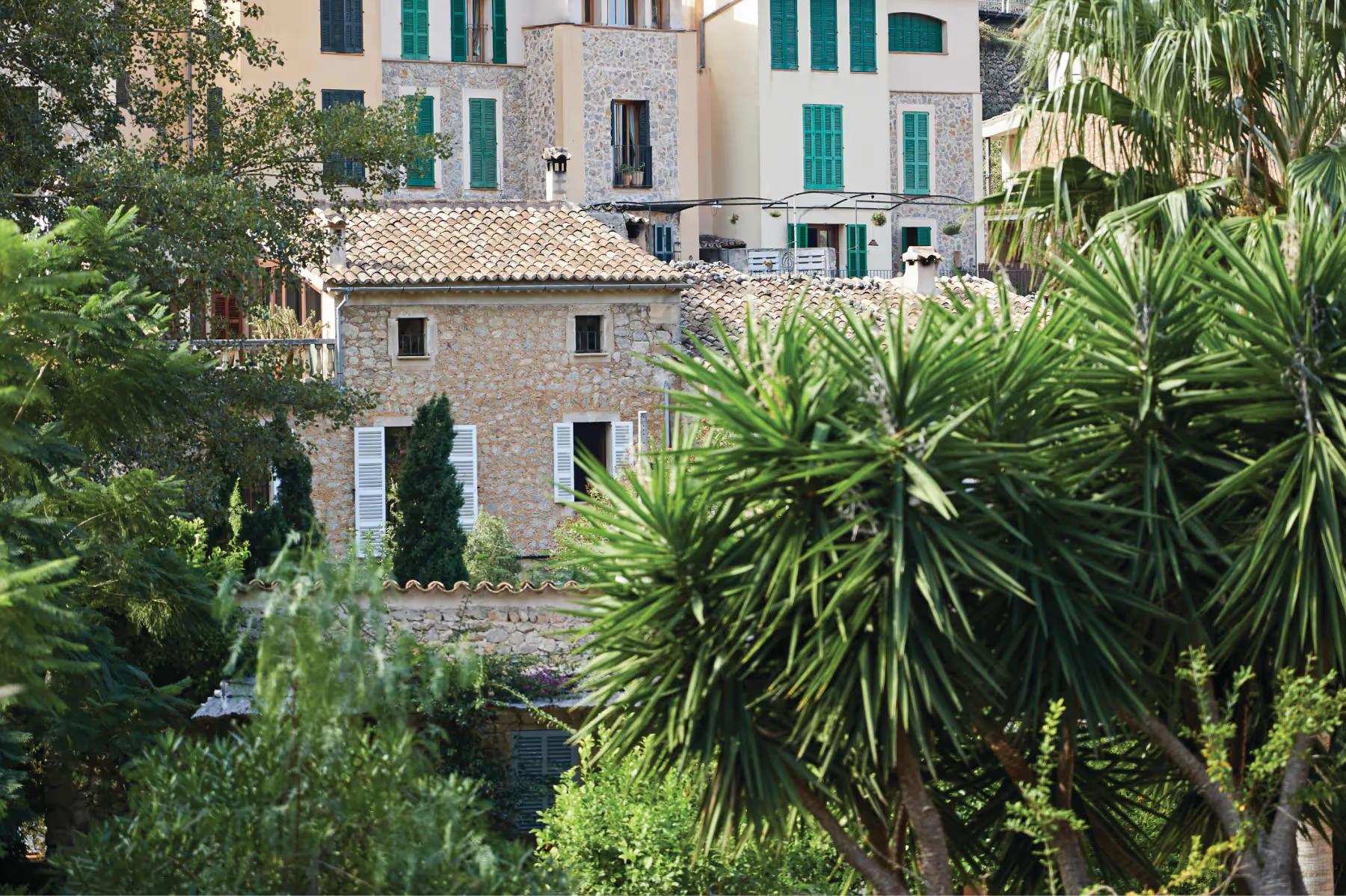 La Residencia: stone buildings with green shutters set among palm and cypress trees in village setting