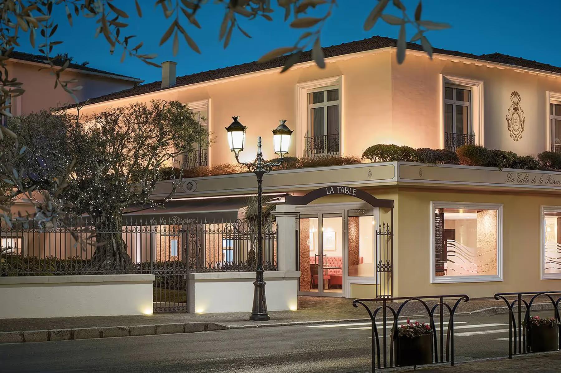 La Réserve de Beaulieu: elegant restaurant entrance lit at dusk with architectural details