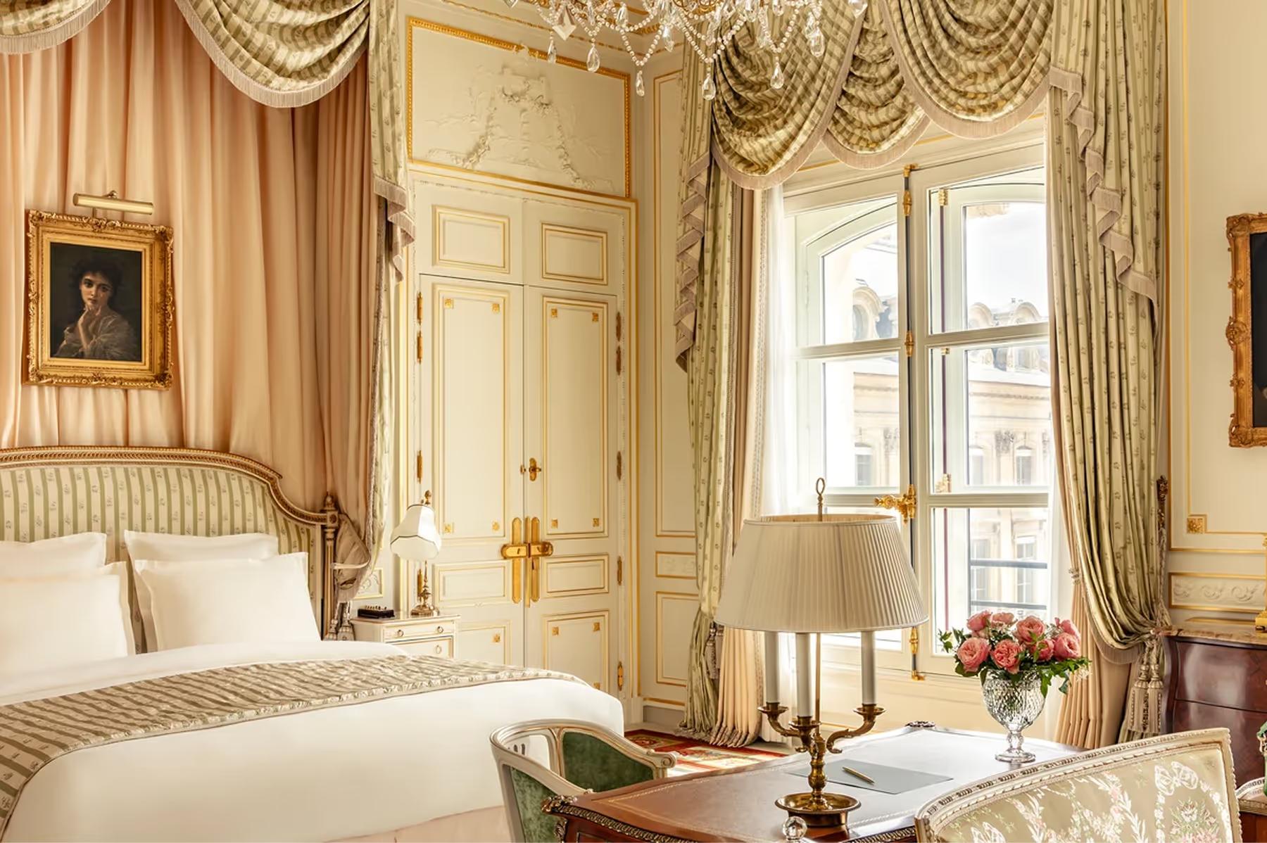 Ritz Paris: a bedroom with draped gold curtains, gilt cove ceiling, damask wallpaper, and cream bedding