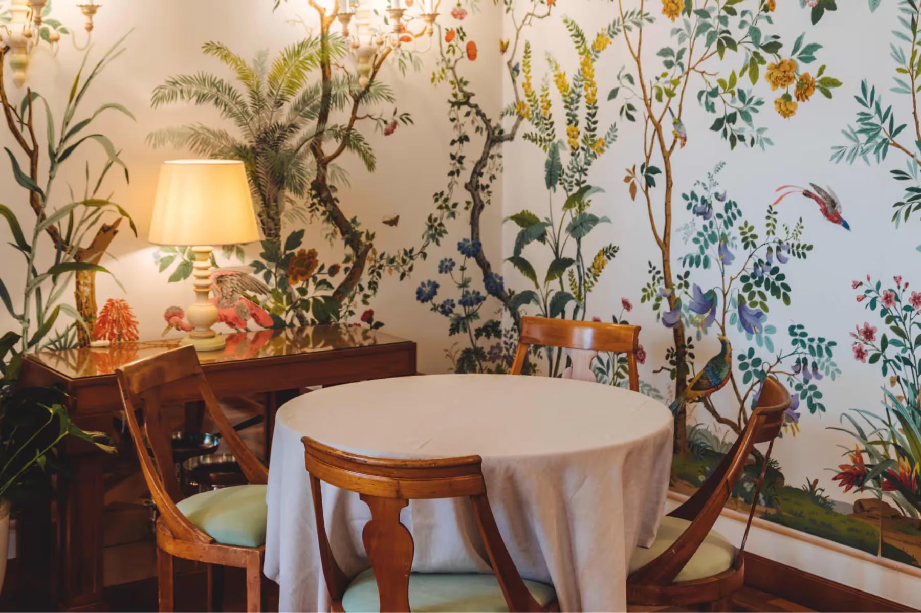 Splendido: an intimate dining room with wallpapered walls, potted plants, and round table