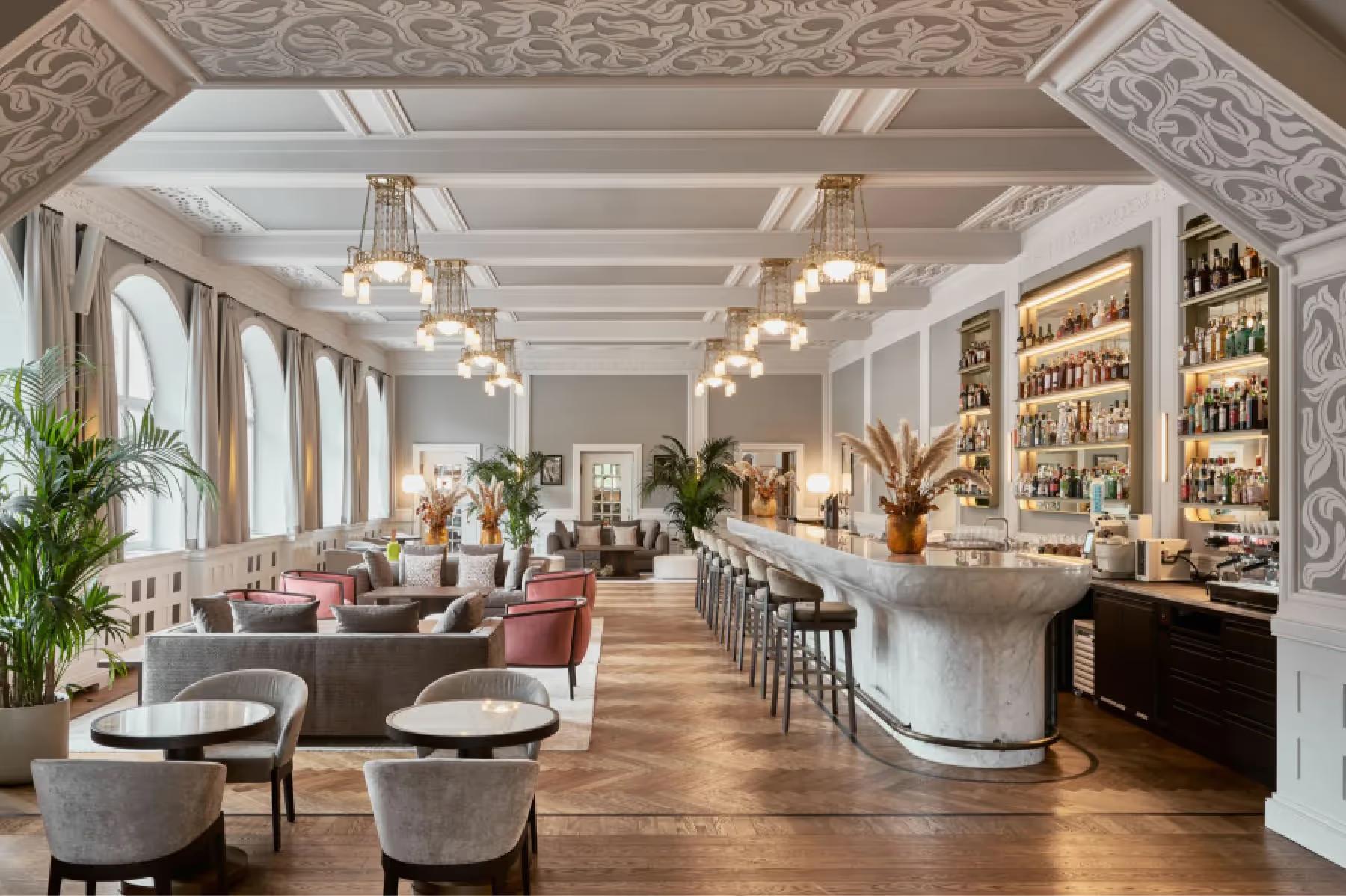 Grace La Margna St. Moritz: elegant dining room with ornate ceiling, hanging pendants, built-in shelving, and round tables