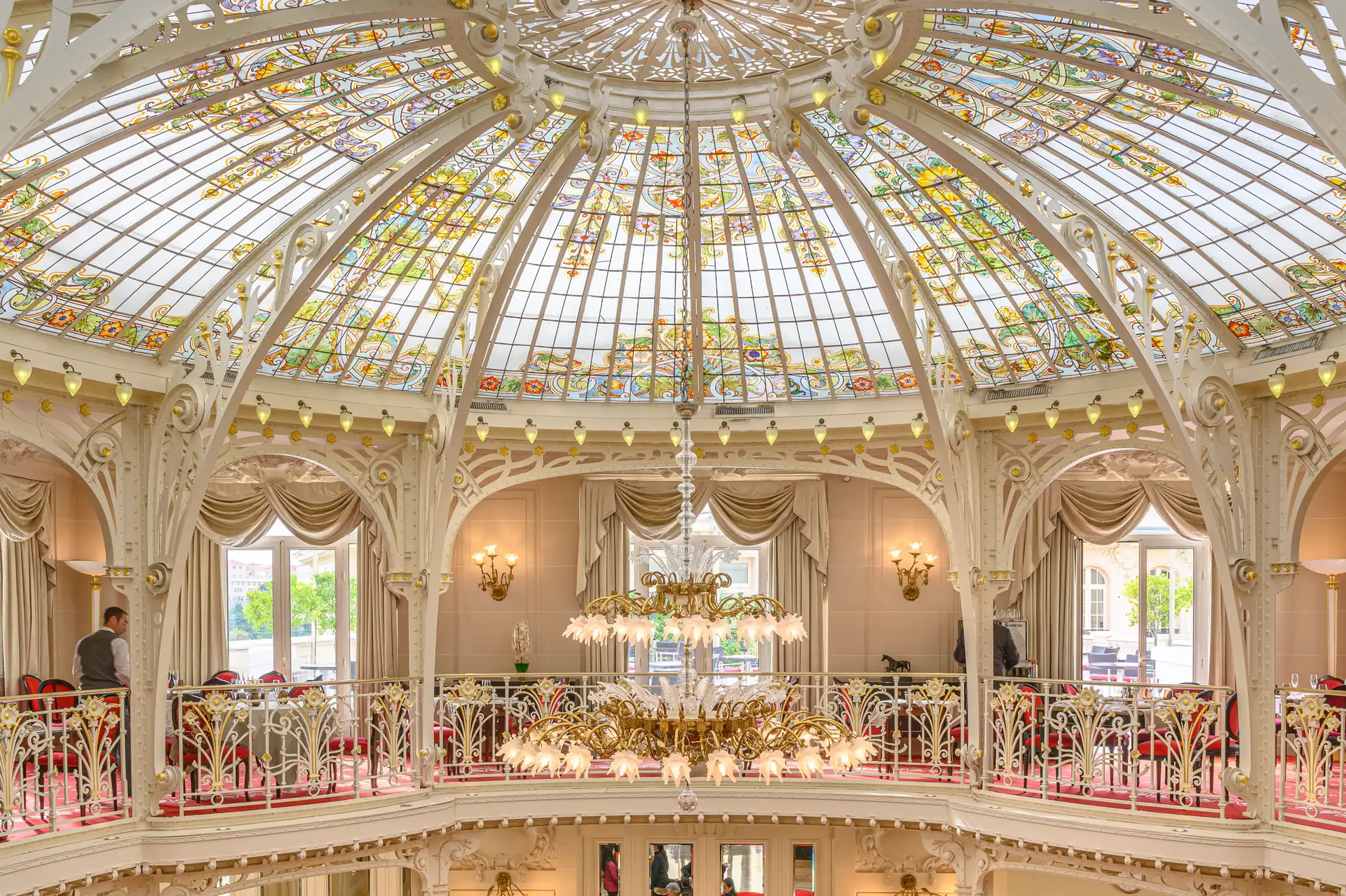 Historic glass-domed winter garden ballroom with cream and red upholstered seating